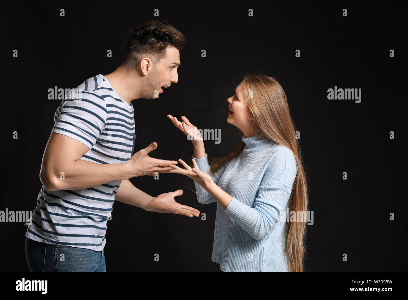 Young quarrelling couple on dark background Stock Photo