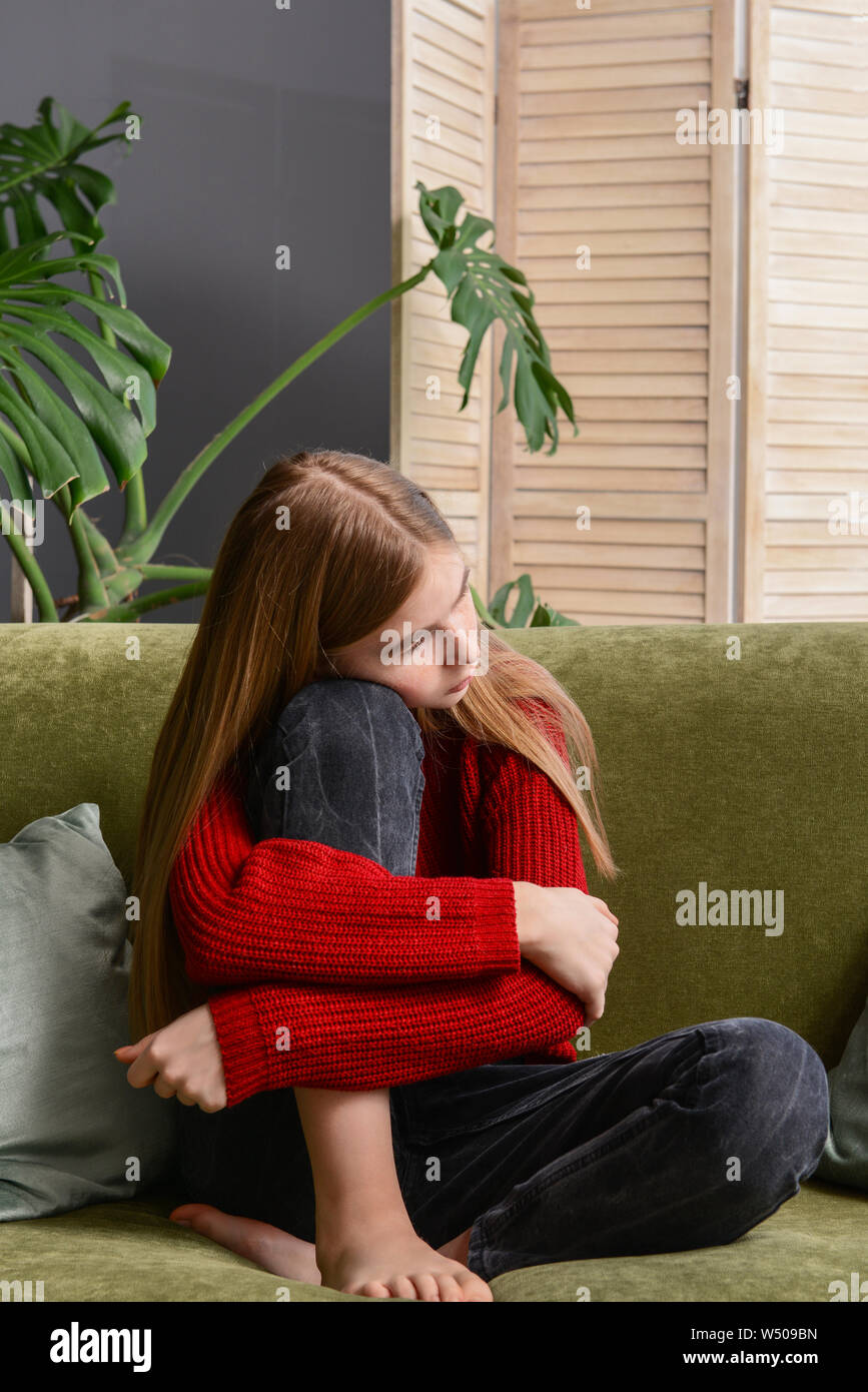 Sad teenage girl sitting on sofa at home Stock Photo - Alamy