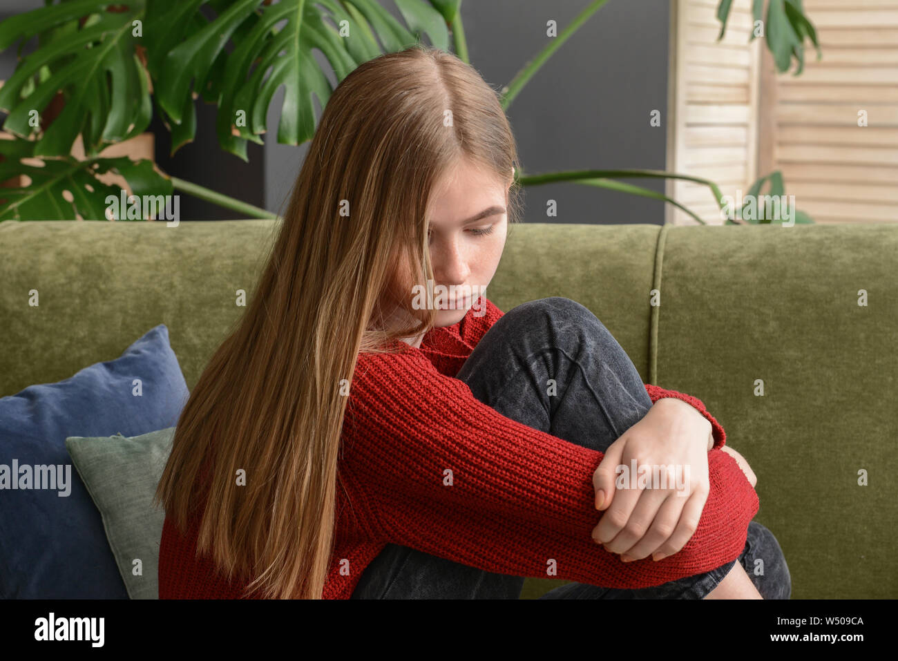 Sad teenage girl sitting on sofa at home Stock Photo - Alamy