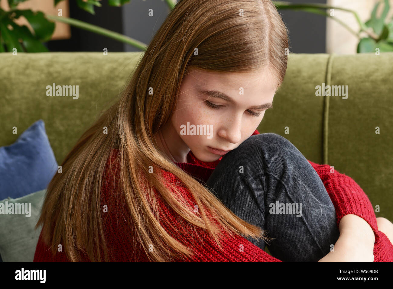 Sad teenage girl sitting on sofa at home Stock Photo - Alamy