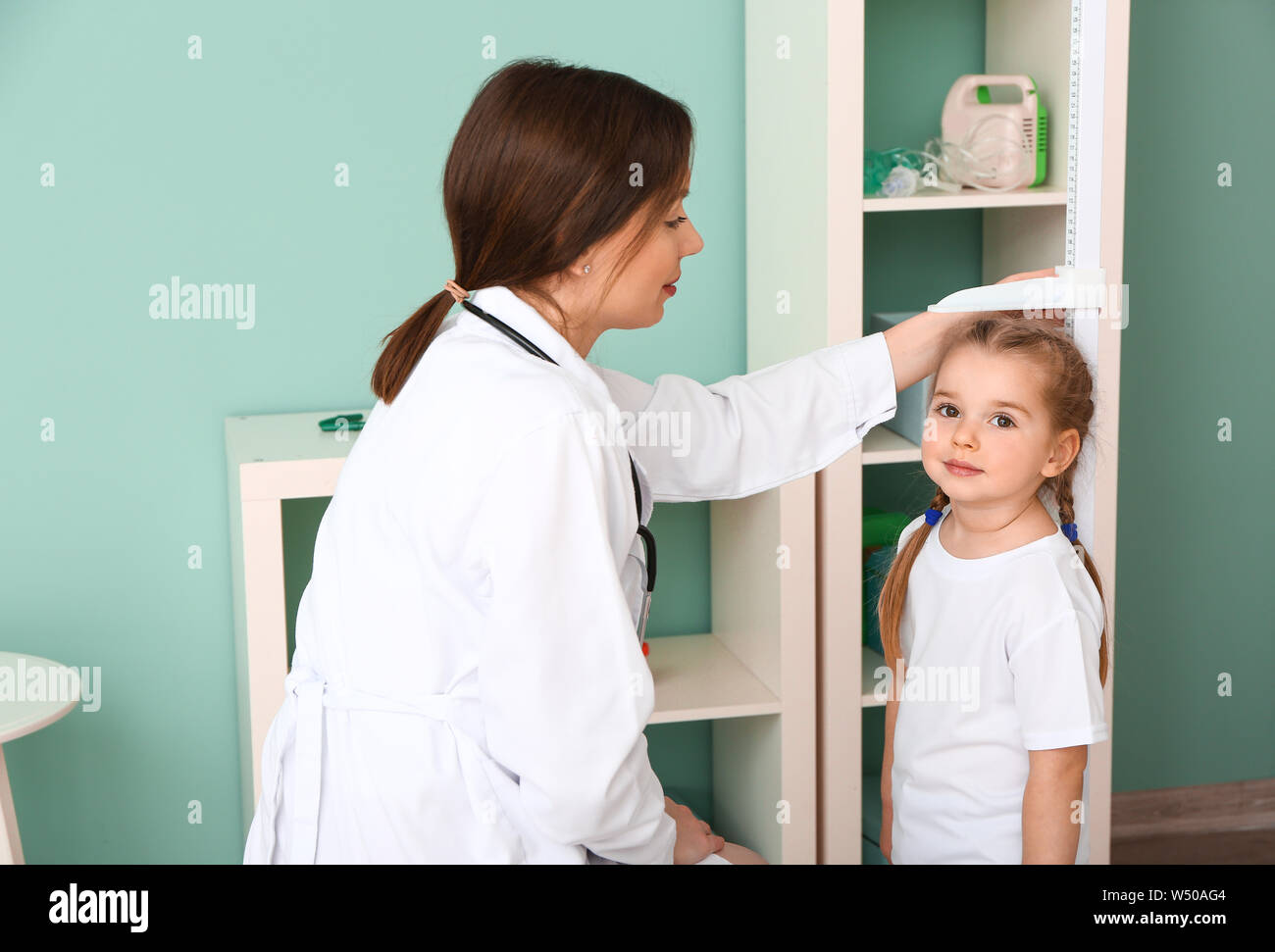 Female doctor measuring height of little girl in hospital Stock Photo