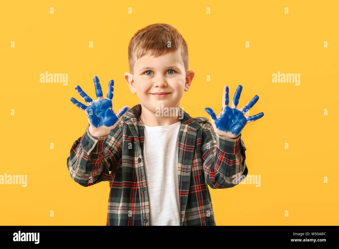 Funny little boy with hands in paint on color background Stock Photo