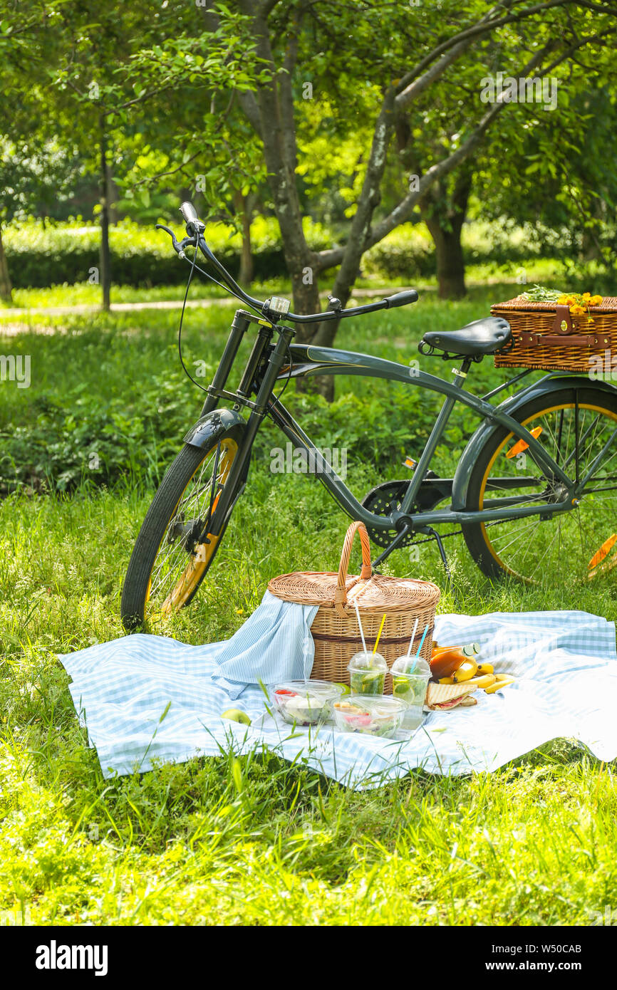 Bicycle and wicker basket with tasty food and drink for romantic