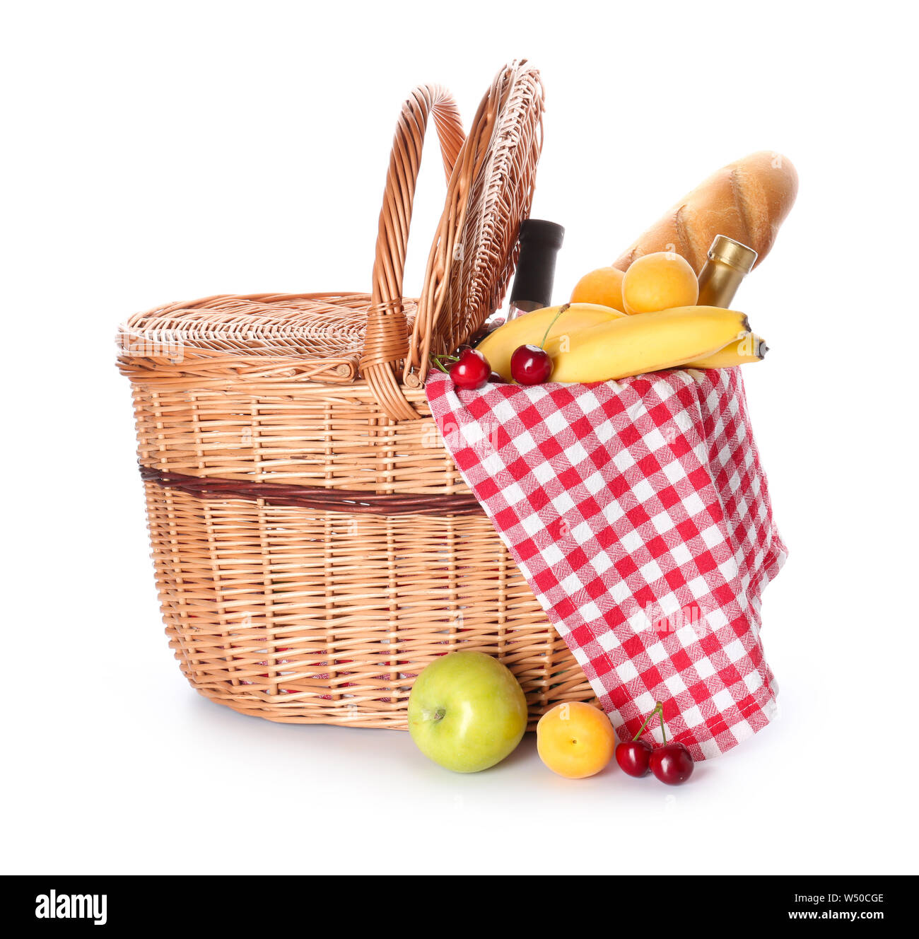 Wicker basket with tasty food and drink for picnic on white background ...
