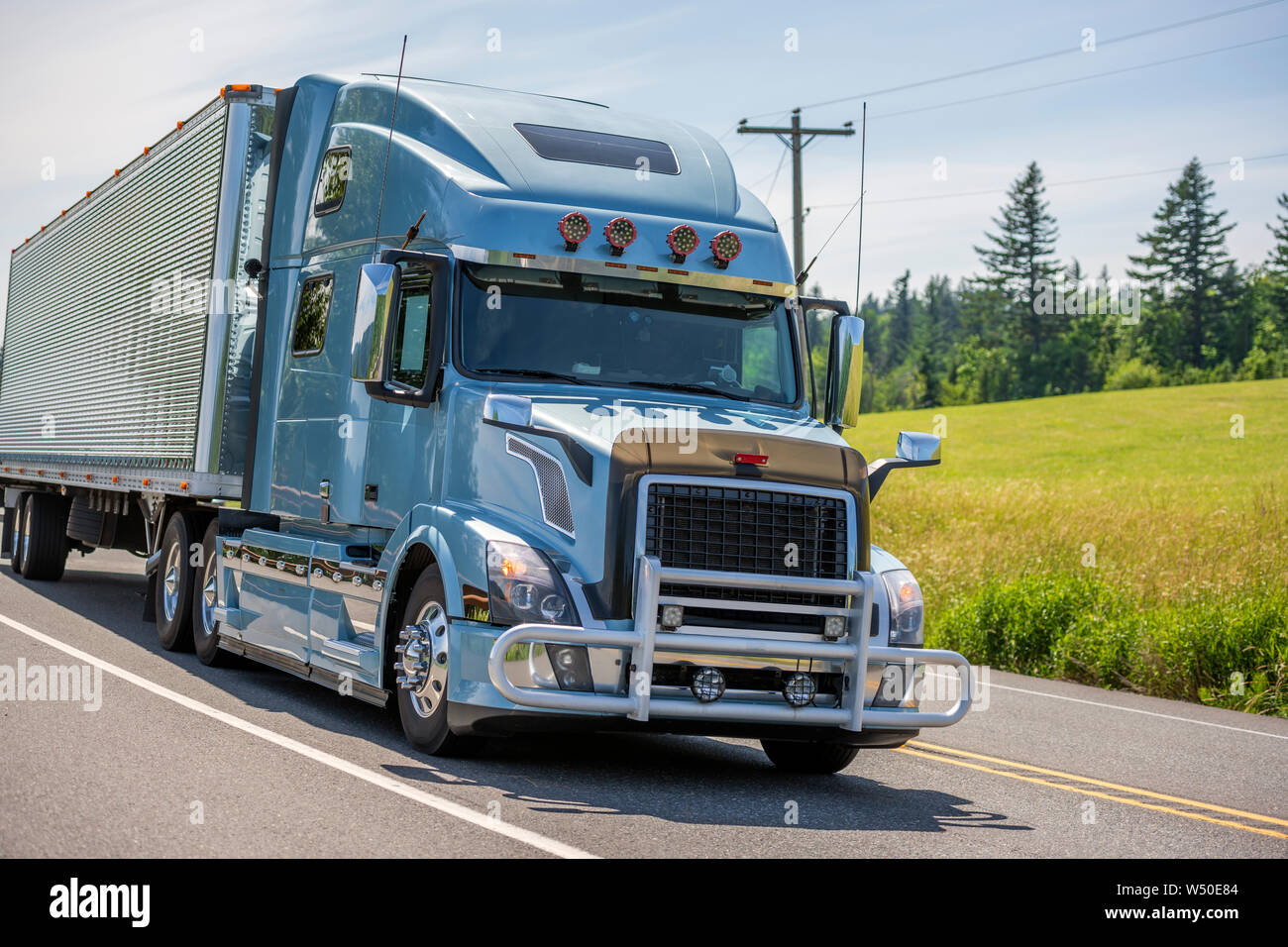 Big rig bonnet long haul blue semi truck with grille guard and chrome accessories transporting frozen commercial cargo in grooved refrigerated semi tr Stock Photo