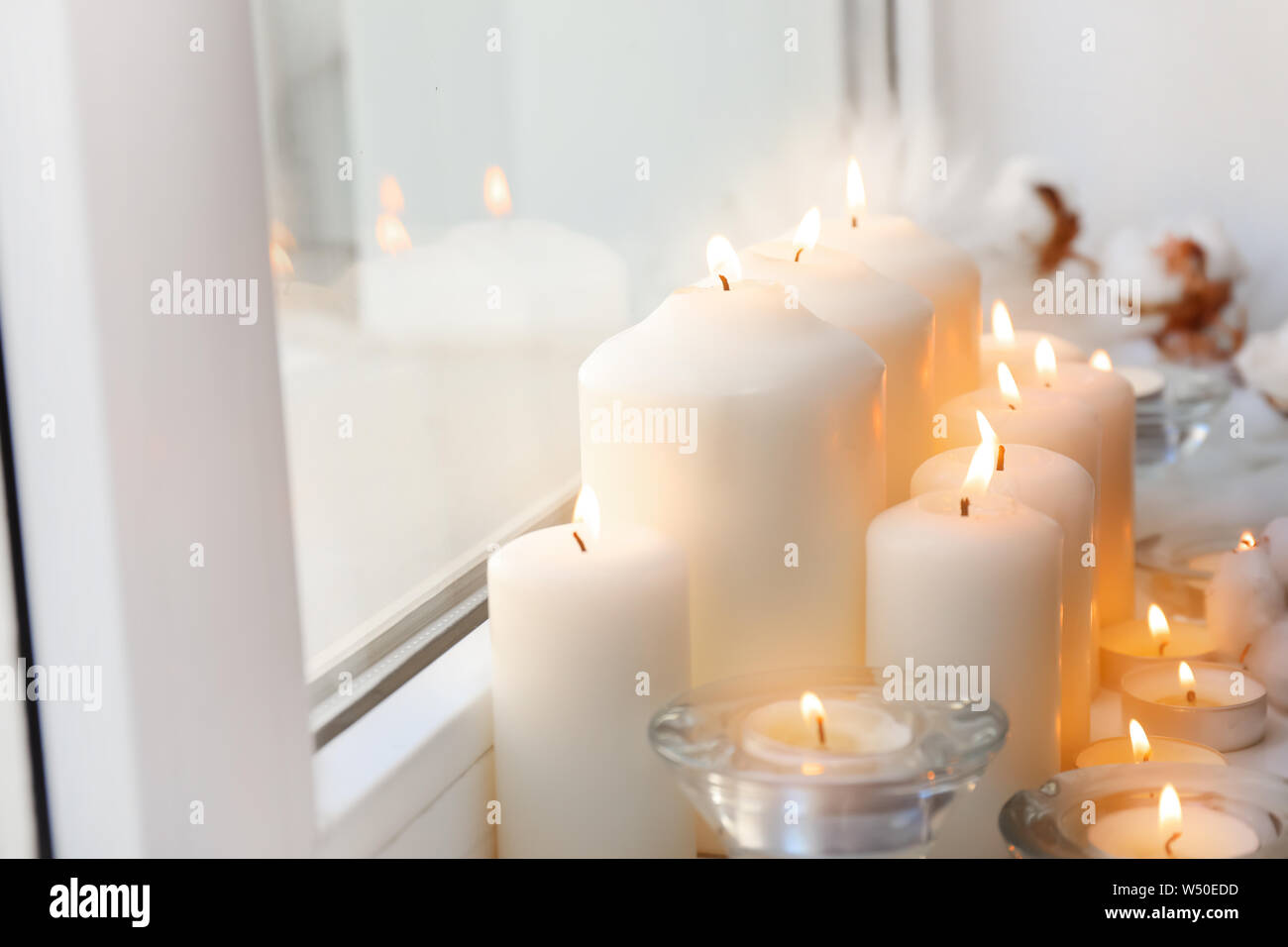 Beautiful burning candles on window sill Stock Photo - Alamy