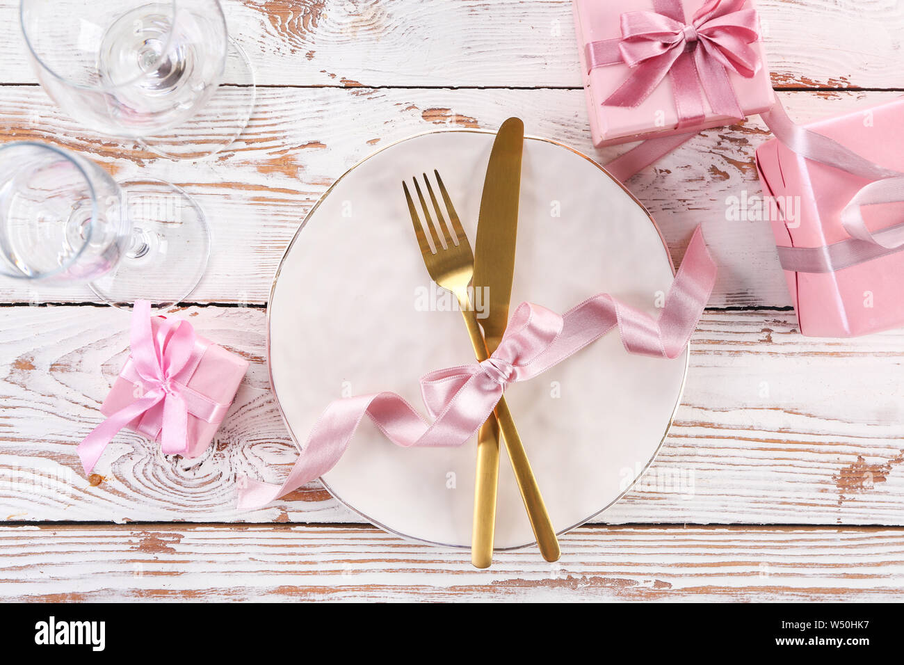 Beautiful table setting with gift boxes on white wooden background ...