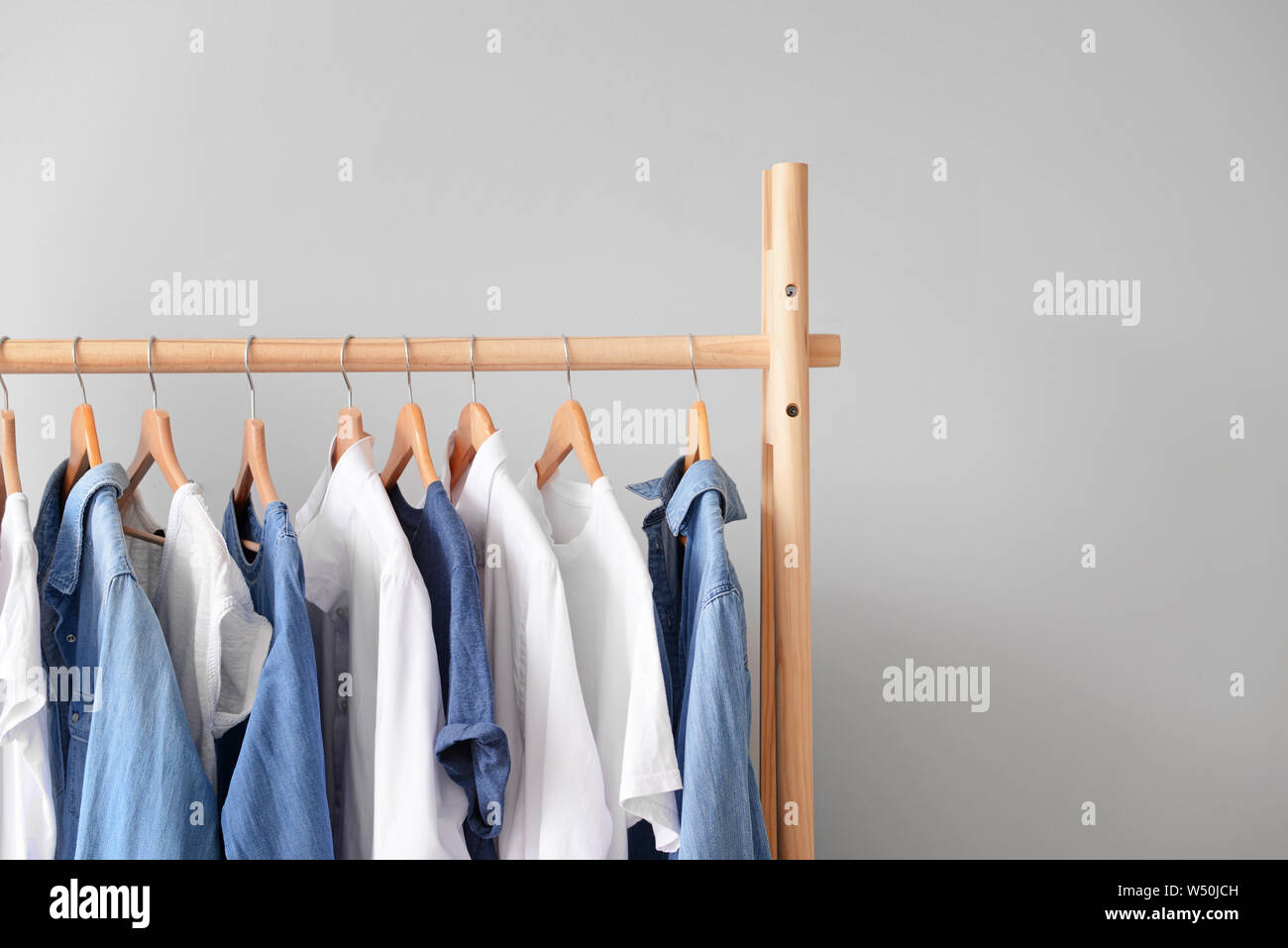 Rack With Hanging Clothes On Light Background Stock Photo