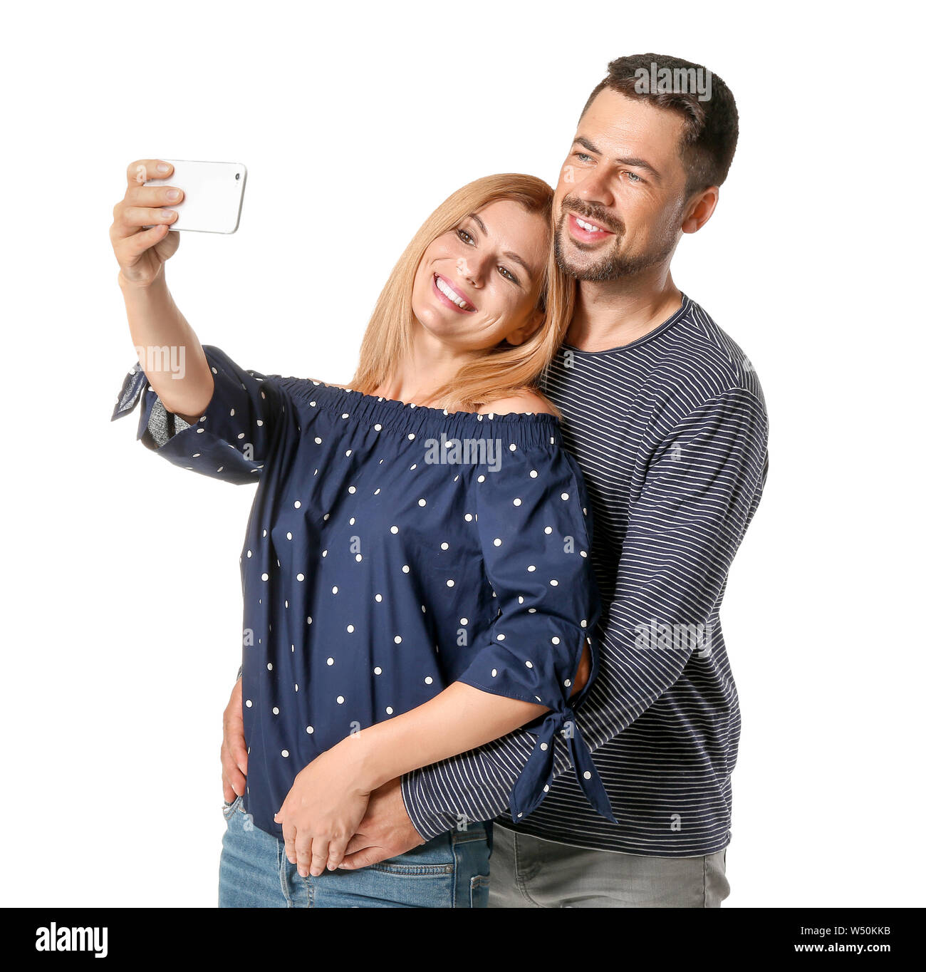 Portrait of happy couple in love taking selfie on white background ...