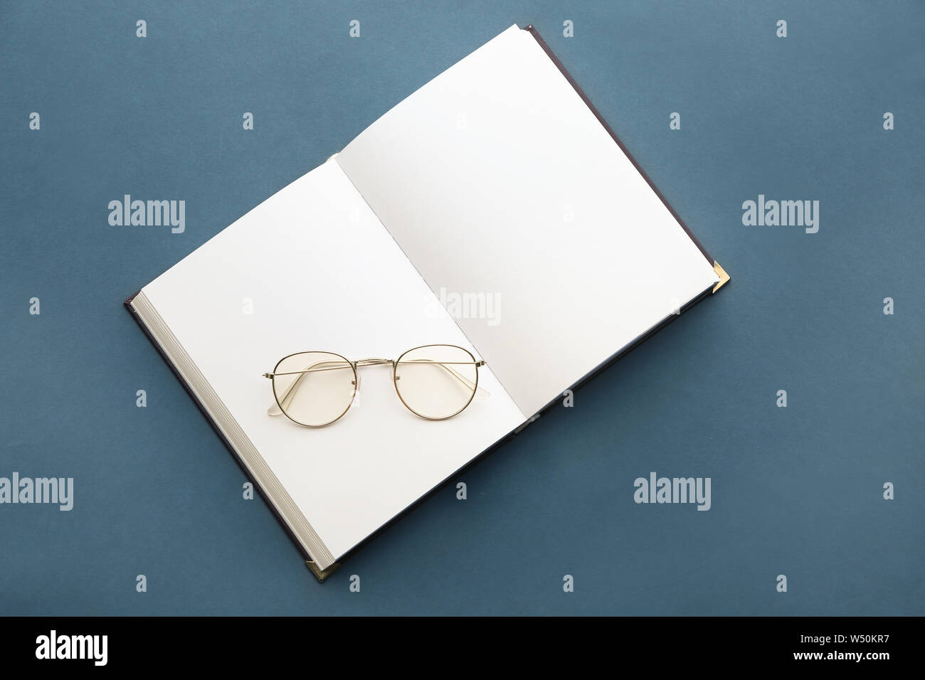Open book with eyeglasses on grey background Stock Photo