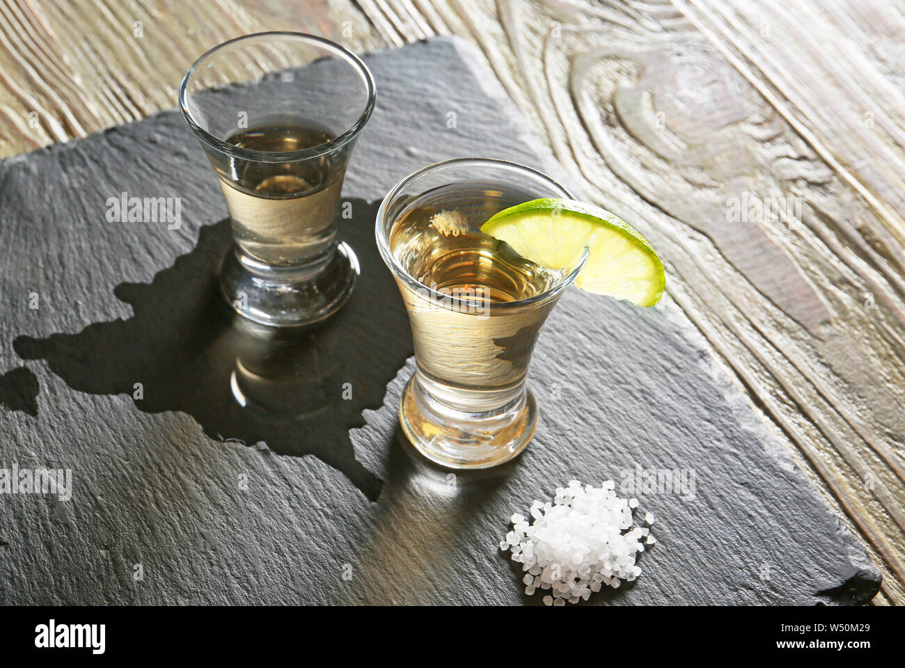 Shots of tasty tequila with lime and salt on slate plate Stock Photo