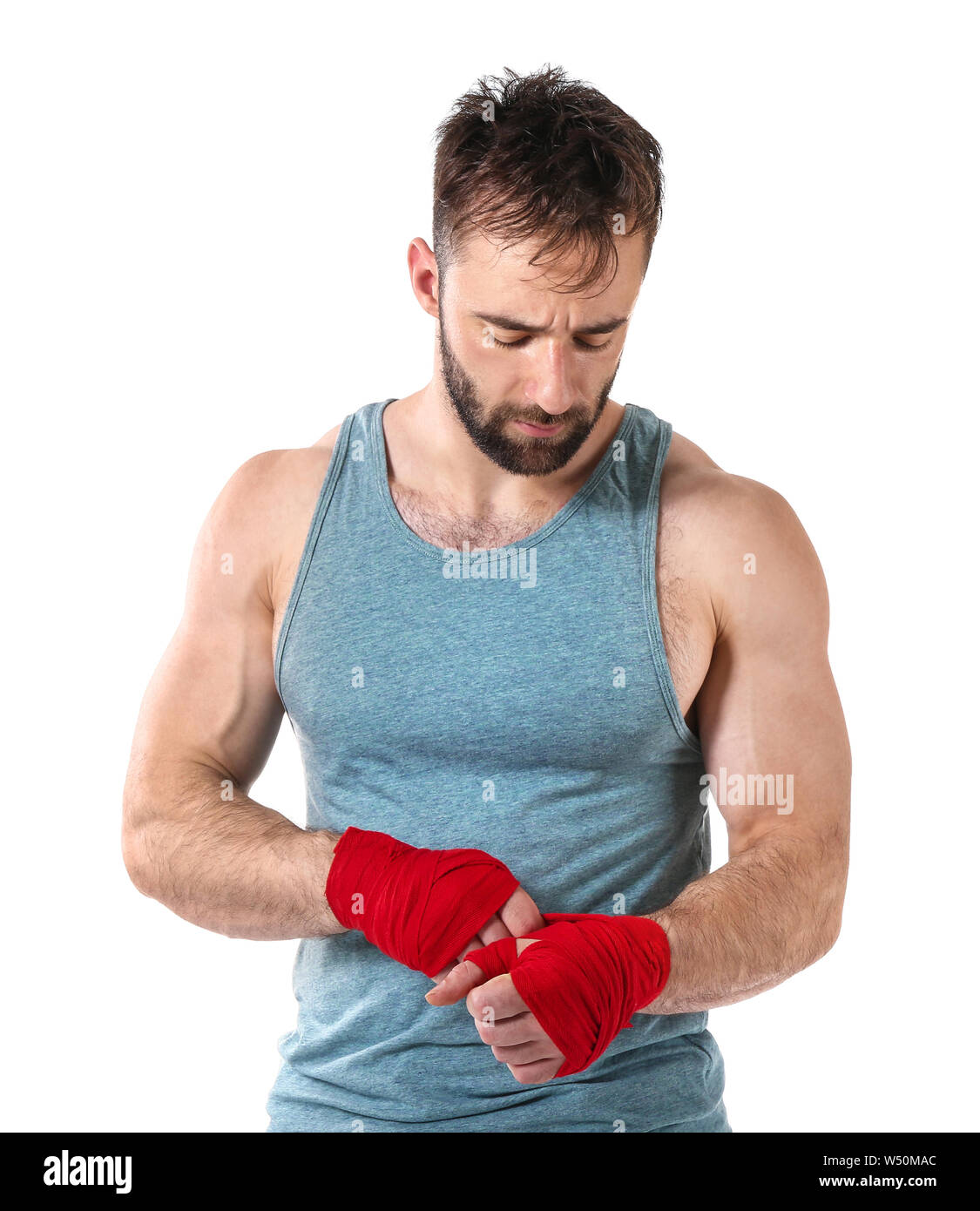 Strong male boxer applying wrist bands against white background Stock