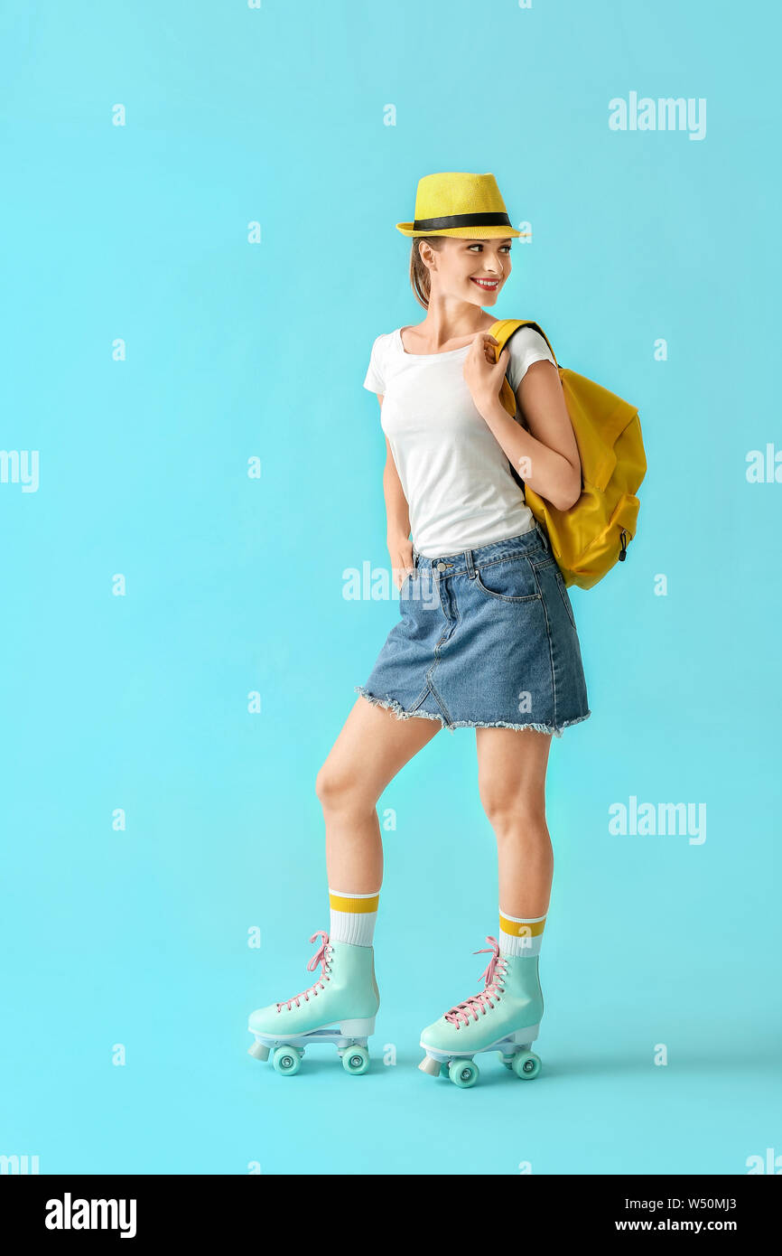 Beautiful young girl on roller skates against color background Stock