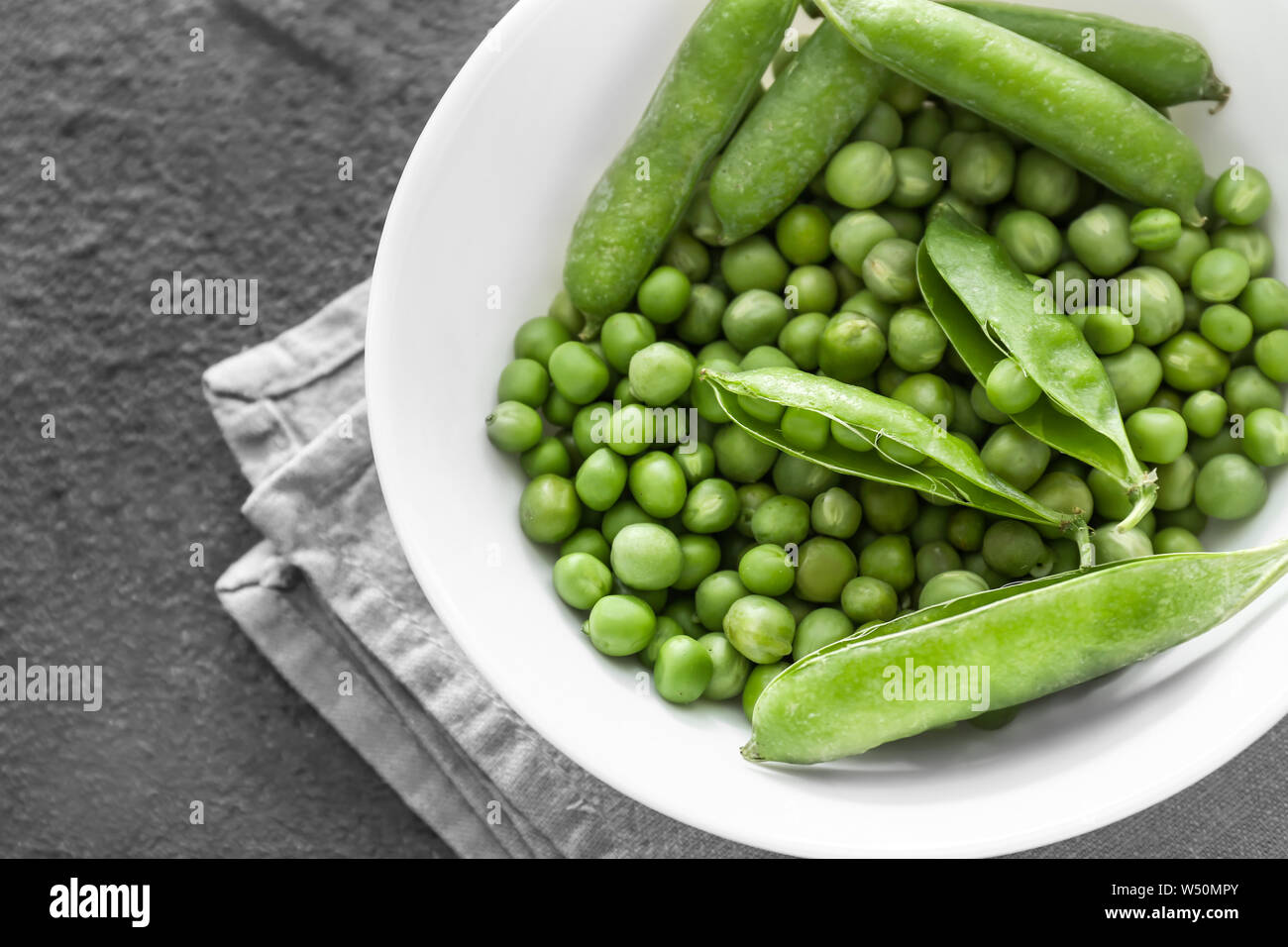 Bowl with tasty fresh peas on dark background Stock Photo