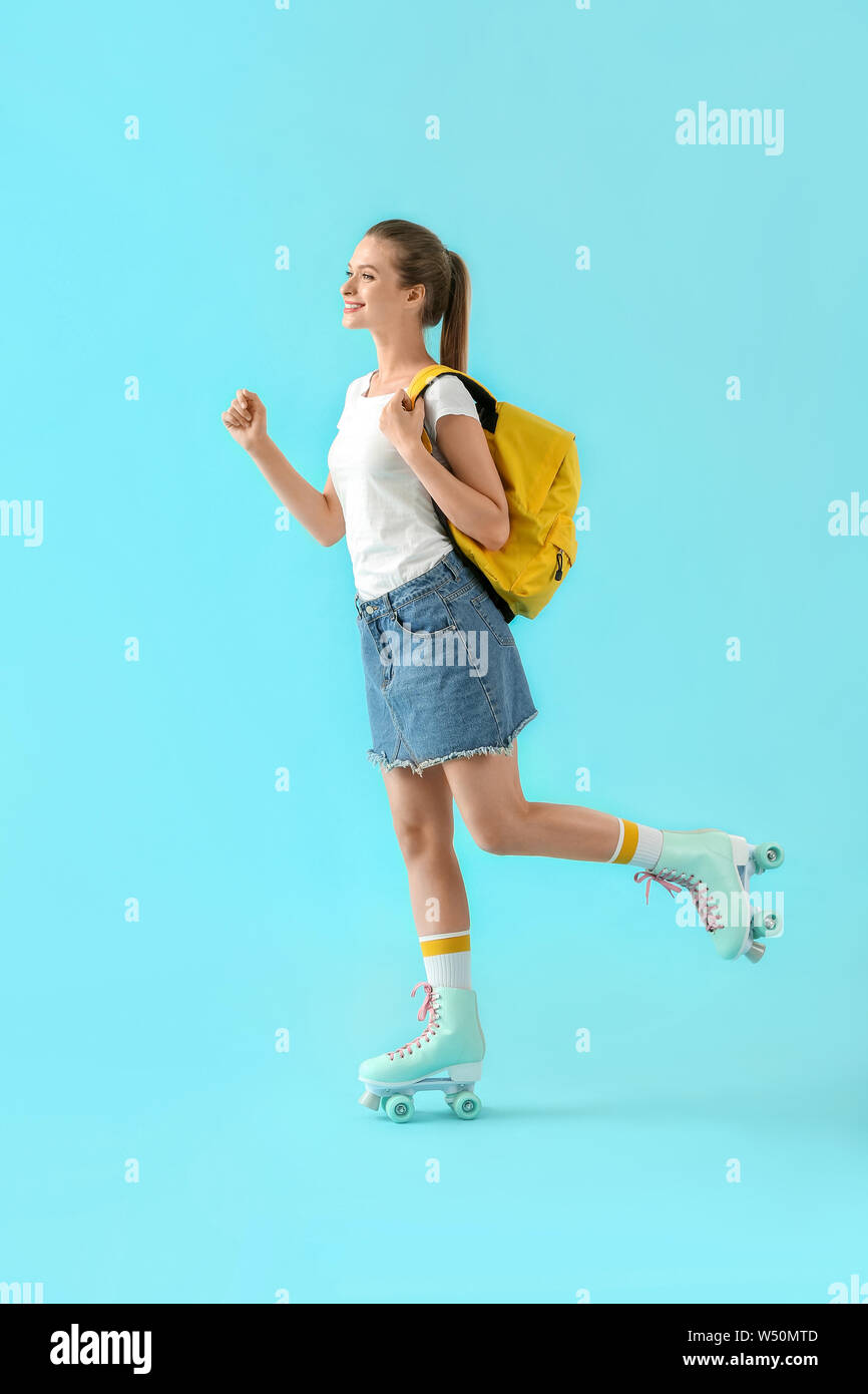 Beautiful young girl on roller skates against color background Stock