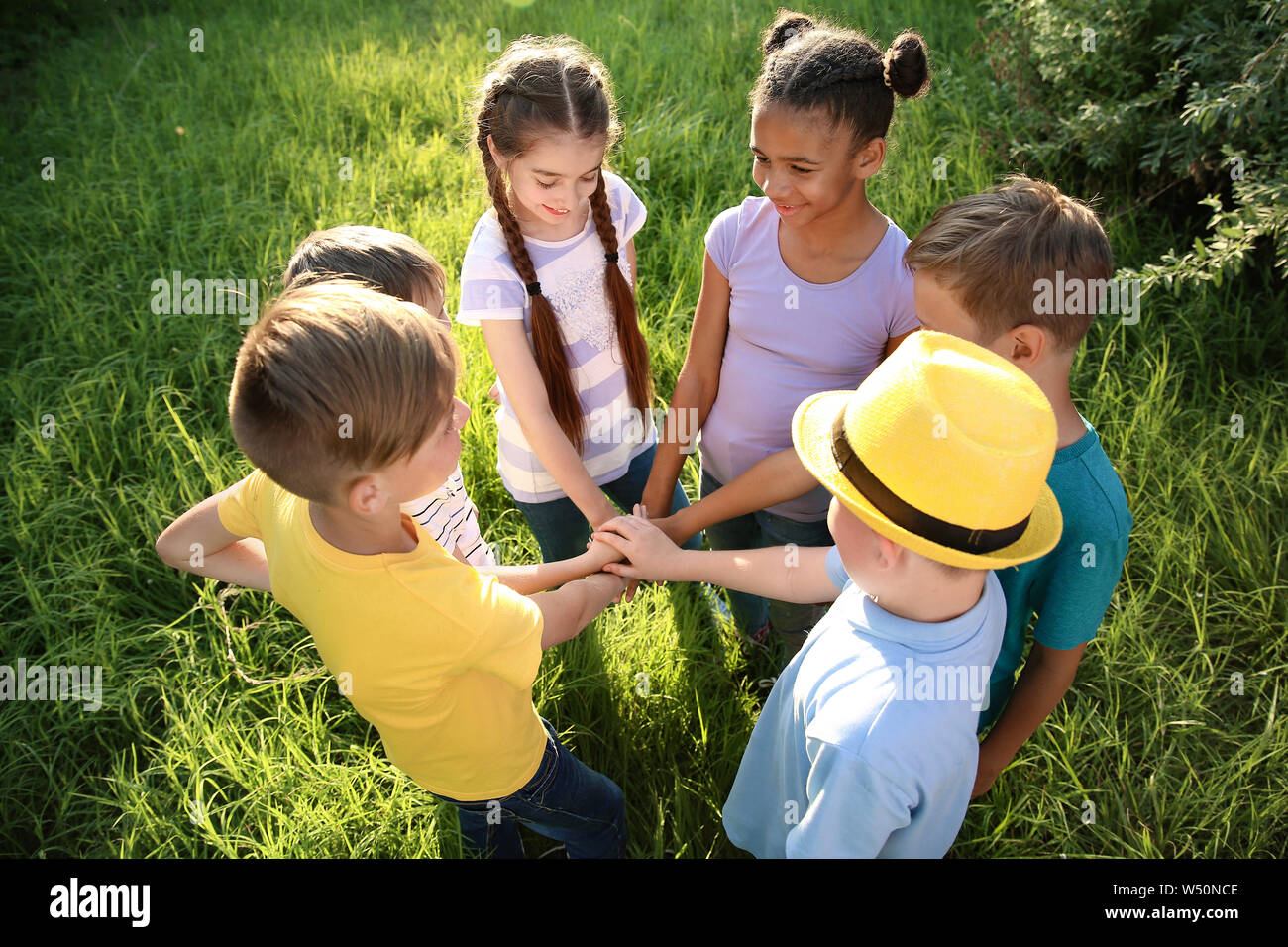 Group of children putting hands together outdoors Stock Photo - Alamy
