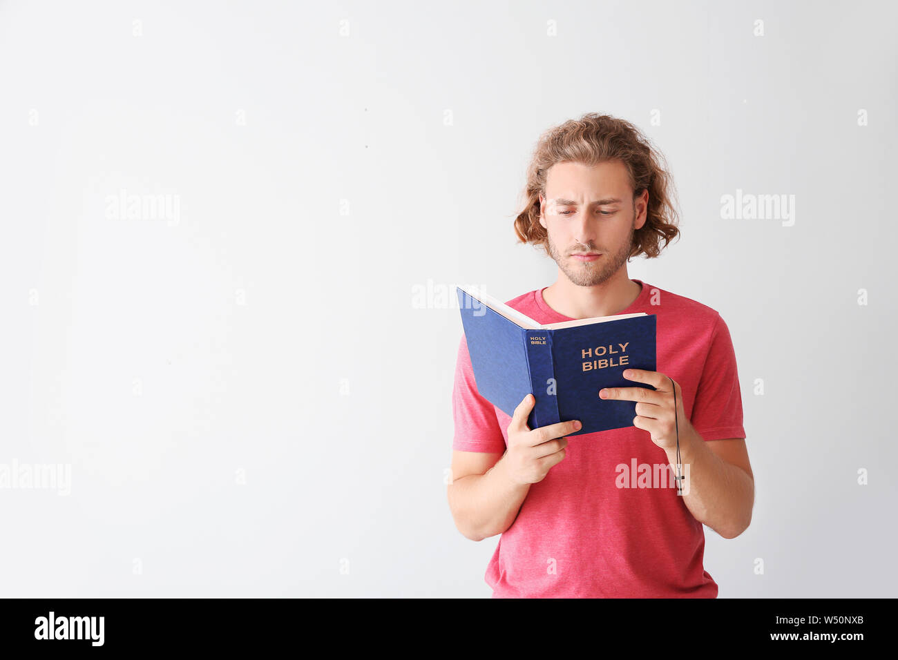 Religious young man reading Bible on white background Stock Photo Alamy