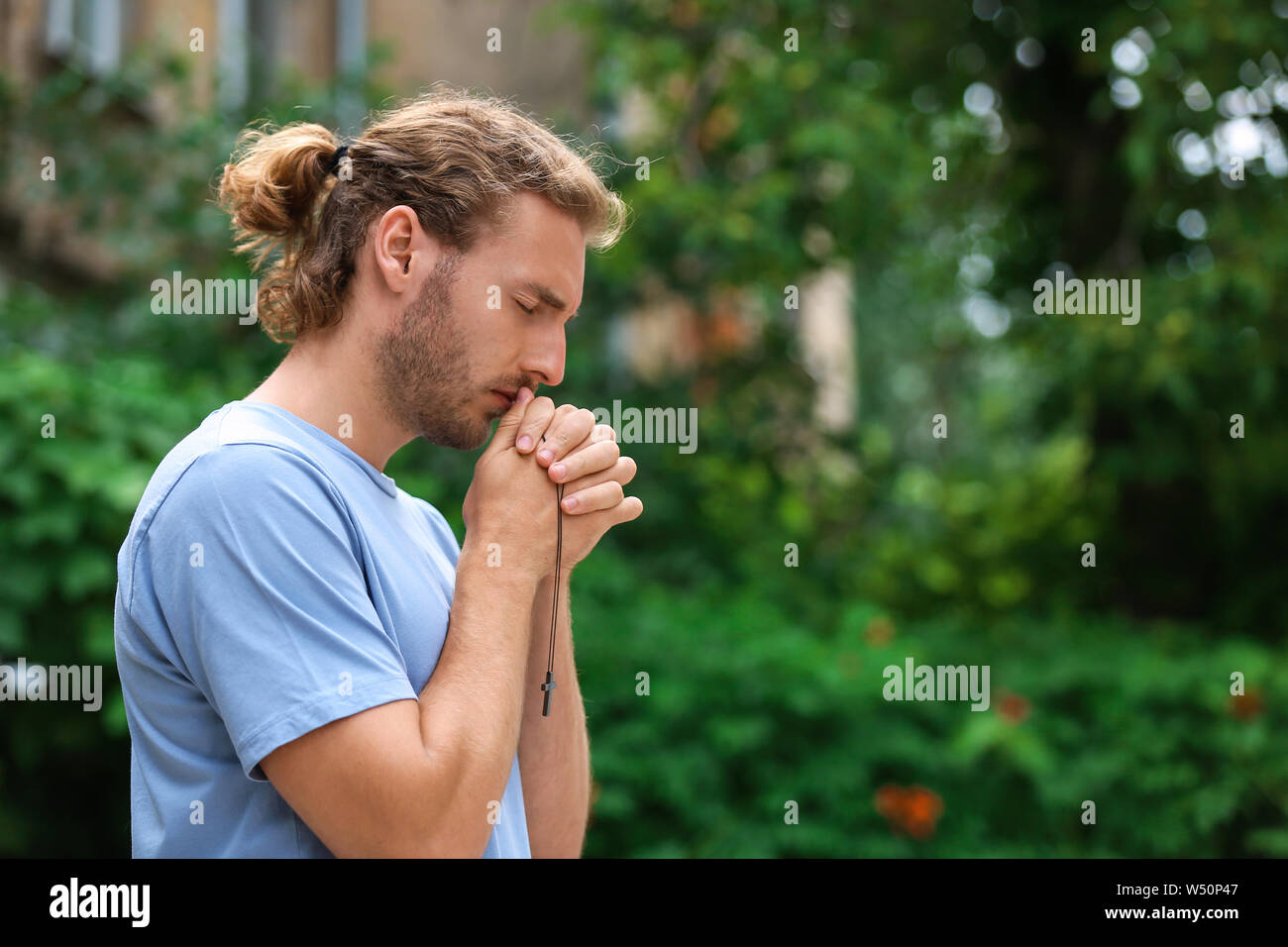 Religious young man praying outdoors Stock Photo Alamy