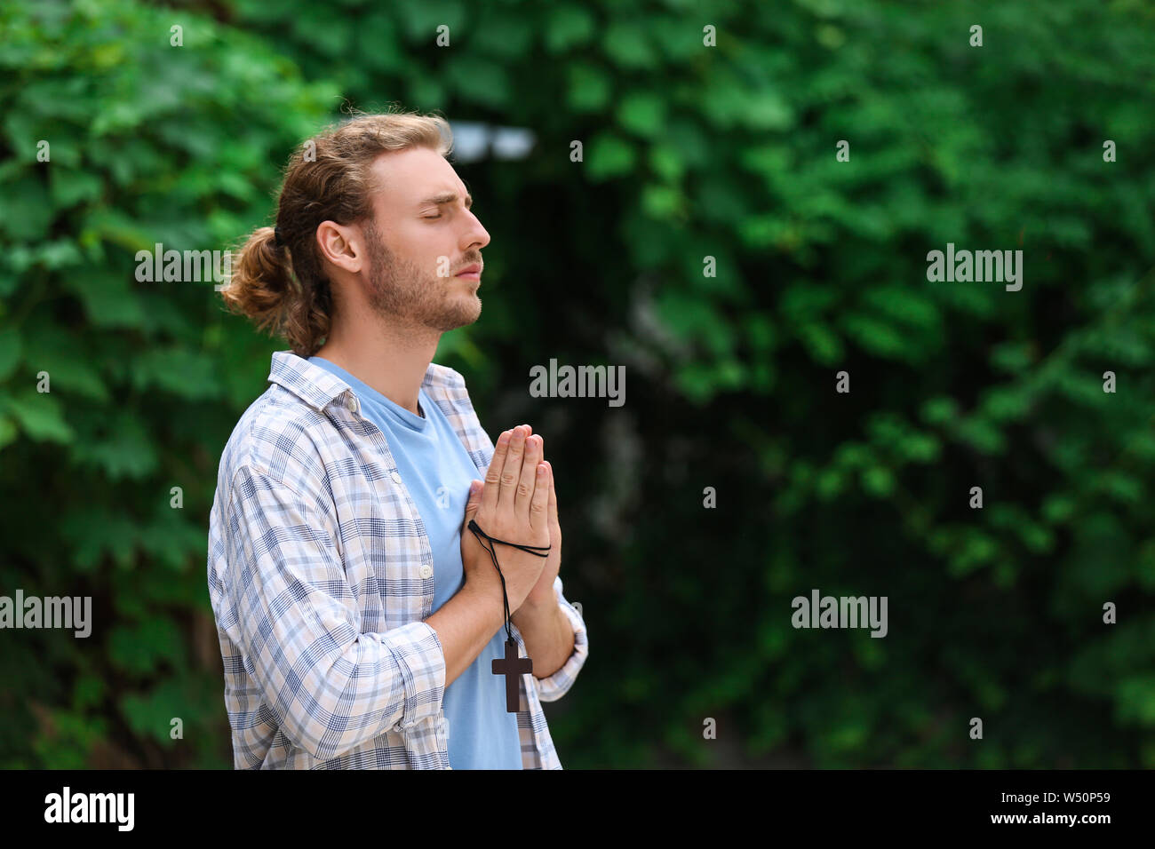 Religious young man praying outdoors Stock Photo Alamy