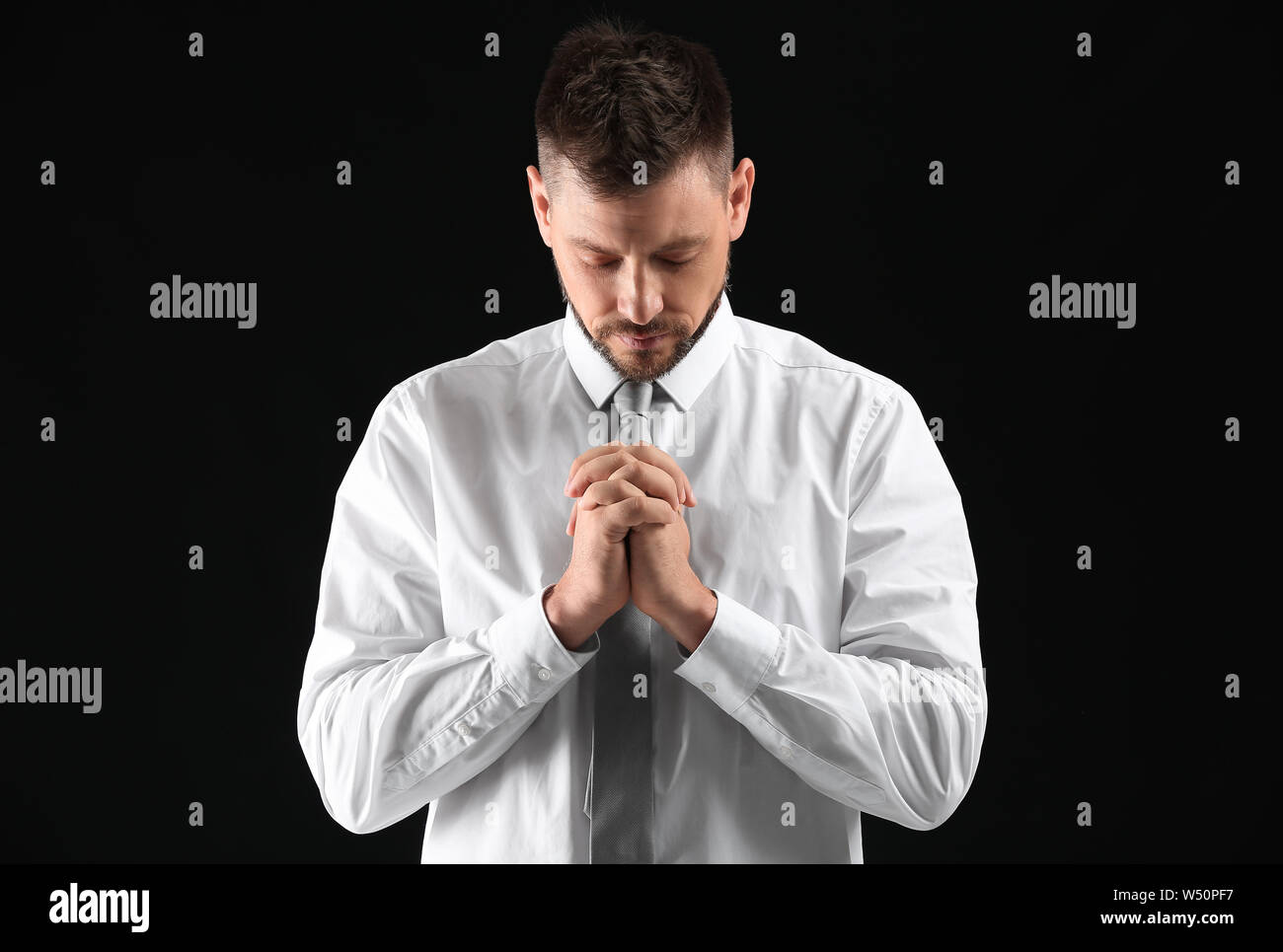 Religious man praying on dark background Stock Photo Alamy