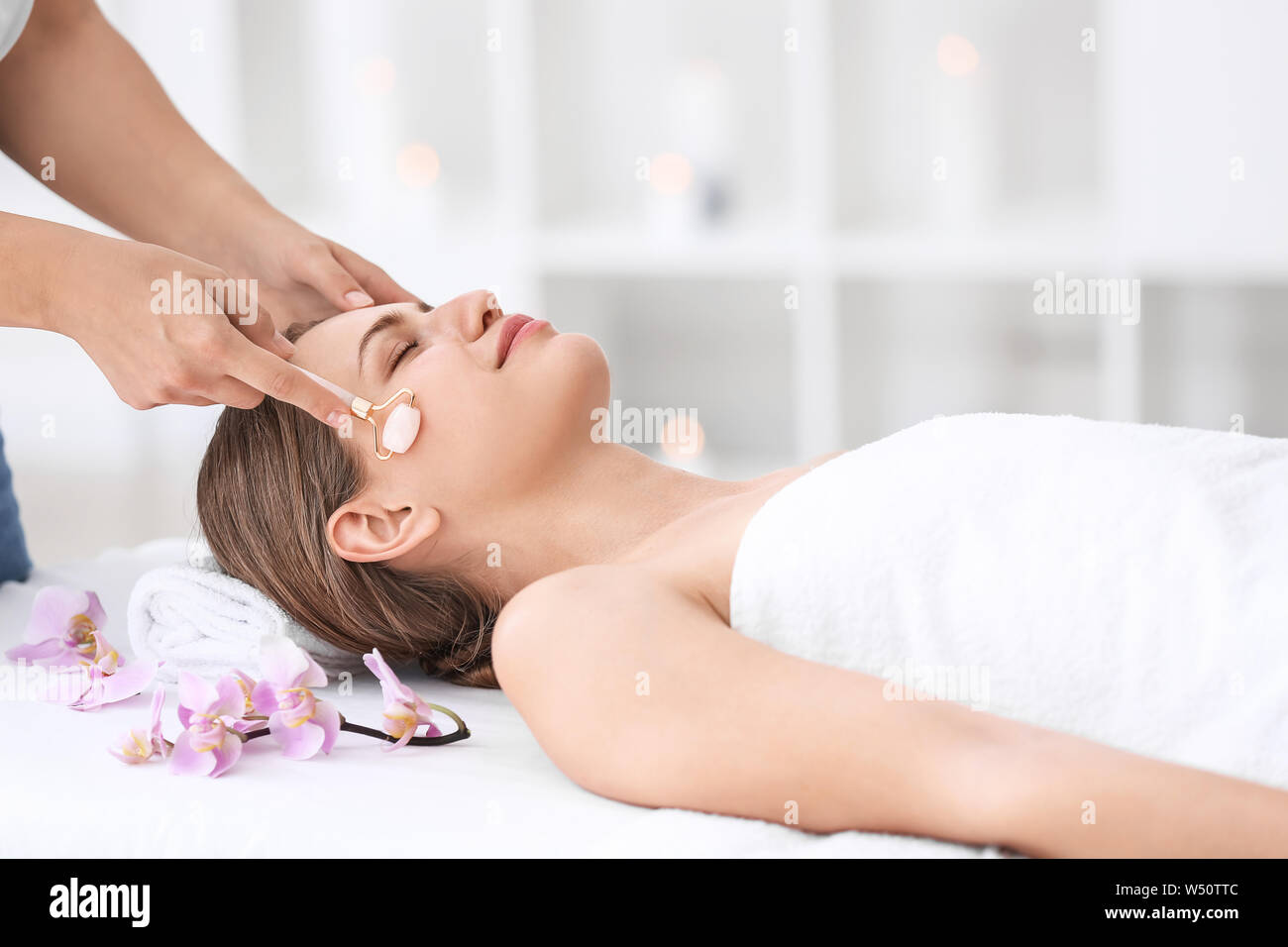 Beautiful young woman receiving facial massage in spa salon Stock Photo