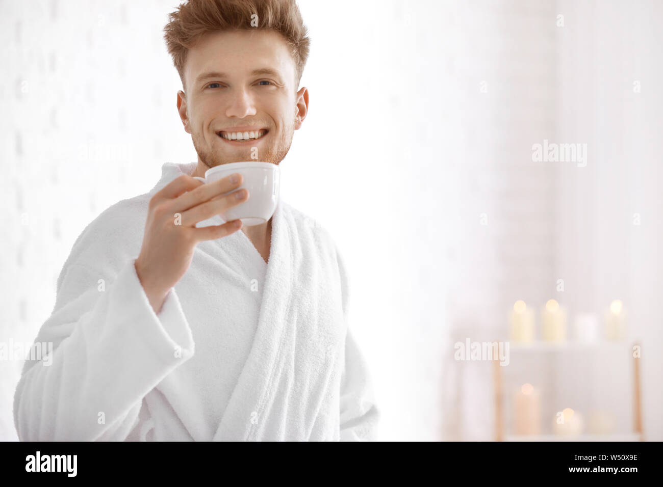 Young man in bathrobe drinking coffee at home Stock Photo