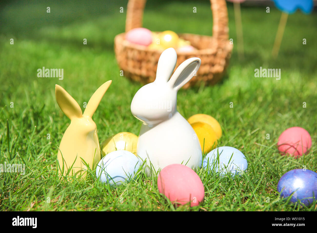 Easter eggs with ceramic bunnies on grass outdoors Stock Photo