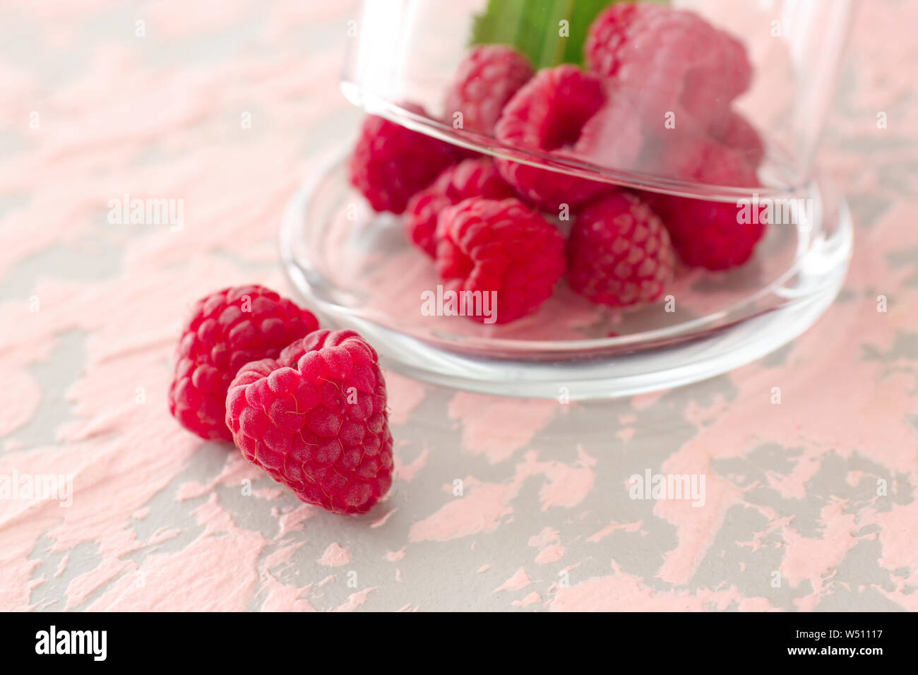 Glass cup and sweet ripe raspberry on color background Stock Photo - Alamy