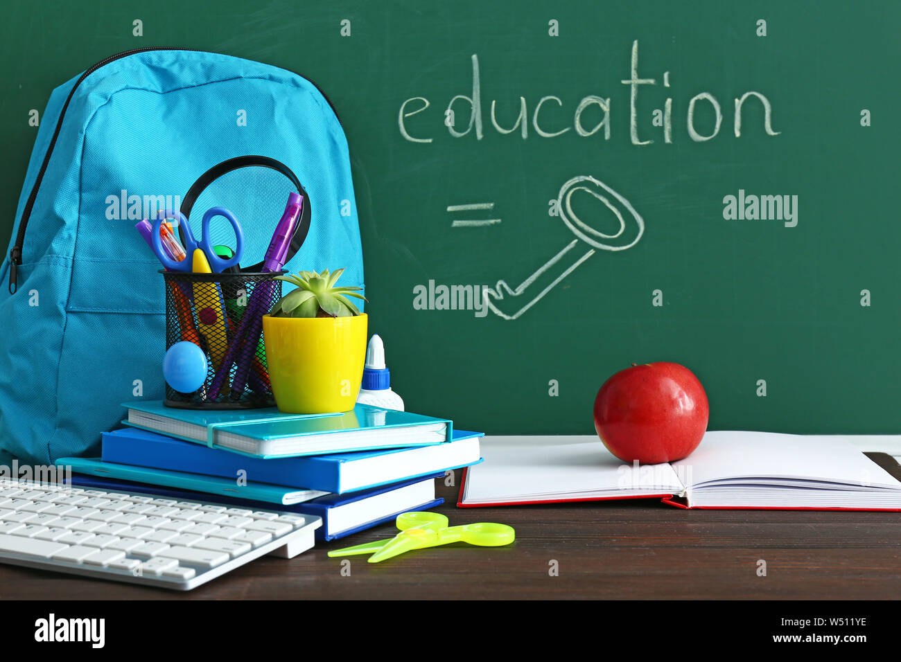 Set of school supplies with backpack on table in classroom Stock Photo