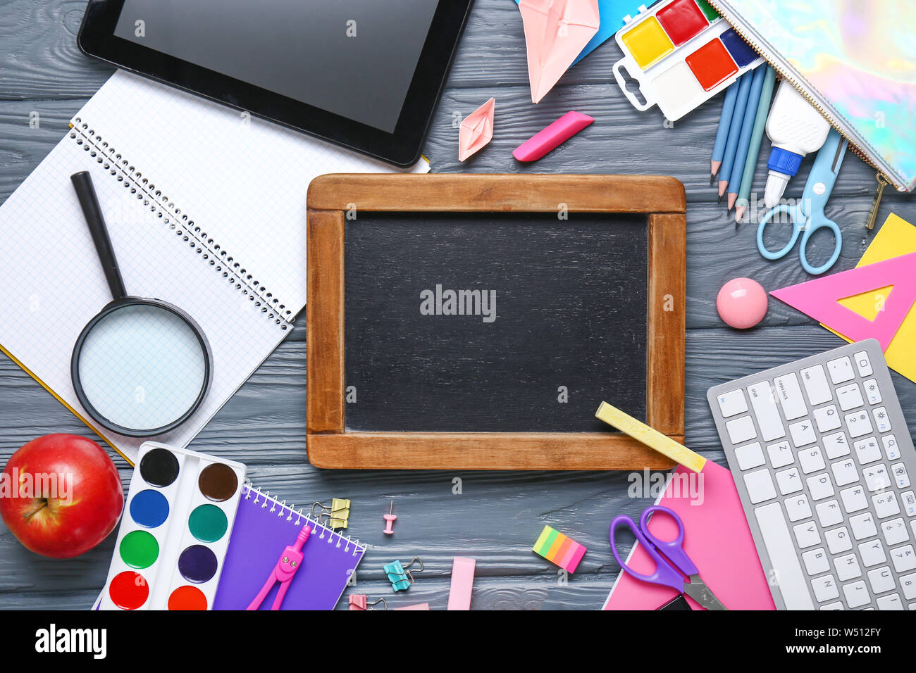 Set of school supplies with chalkboard and computer on wooden ...
