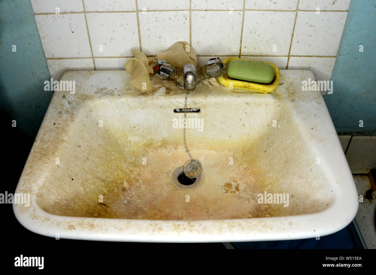 Messy bathroom sink, with dirty tap, soap and wall. Stock Photo