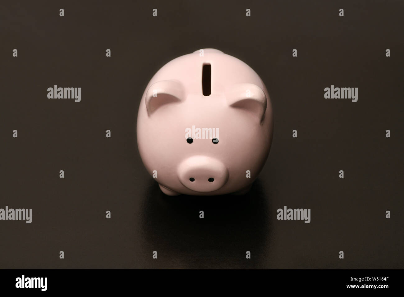 Pink piggy Bank in the shape of a pig stands in the center on a black background. black Friday Stock Photo