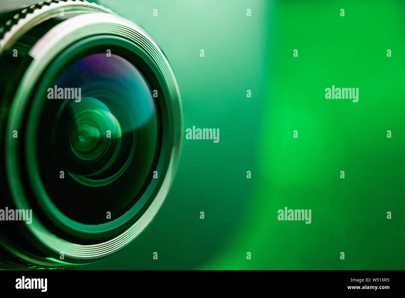 Camera lens with green backlight. Side view of the lens of camera on green background. Greencamera Lens close Up. Pure red Stock Photo