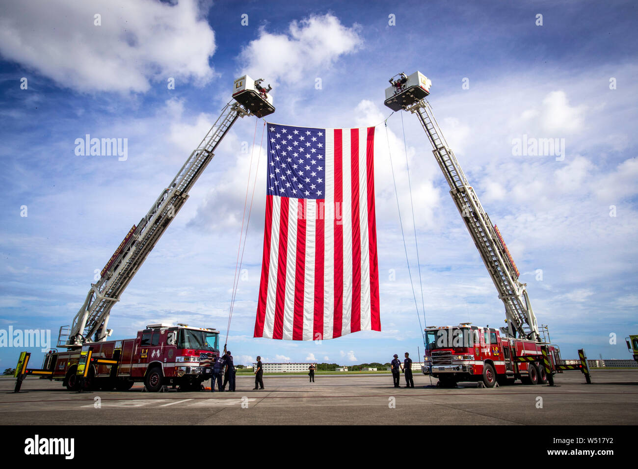 Personnel with Fire and Emergency Services, Marine Corps Installations Pacific - Marine Corps Base Camp Butler, hoist the American flag on Marine Corps Air Station Futenma, July 25, 2019. The personnel with Fire and Emergency Services were attending a practice for a change of command. U.S. Marine Corps Maj. Gen Paul Rock Jr. is scheduled to relinquish his post as Commanding General of Marine Corps Installations Pacific to U.S. Marine Corps Brig. Gen. William J. Bowers on July 26, 2019. (U.S. Marine Corps photo by Lance Cpl. Savannah Mesimer) Stock Photo