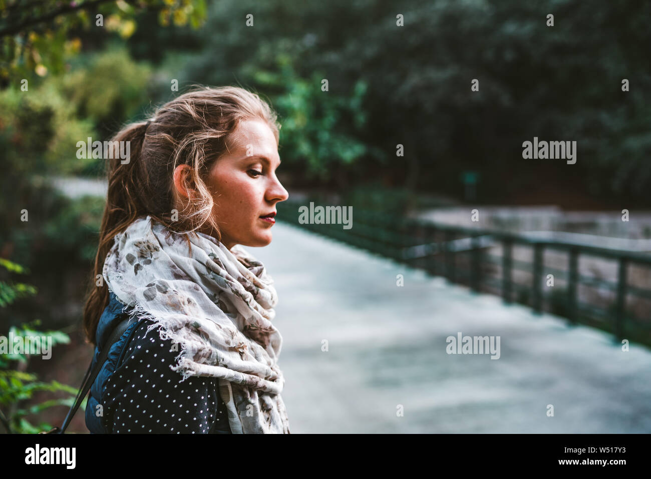 Portrait of beautiful young woman in green park standing on bridge and ...
