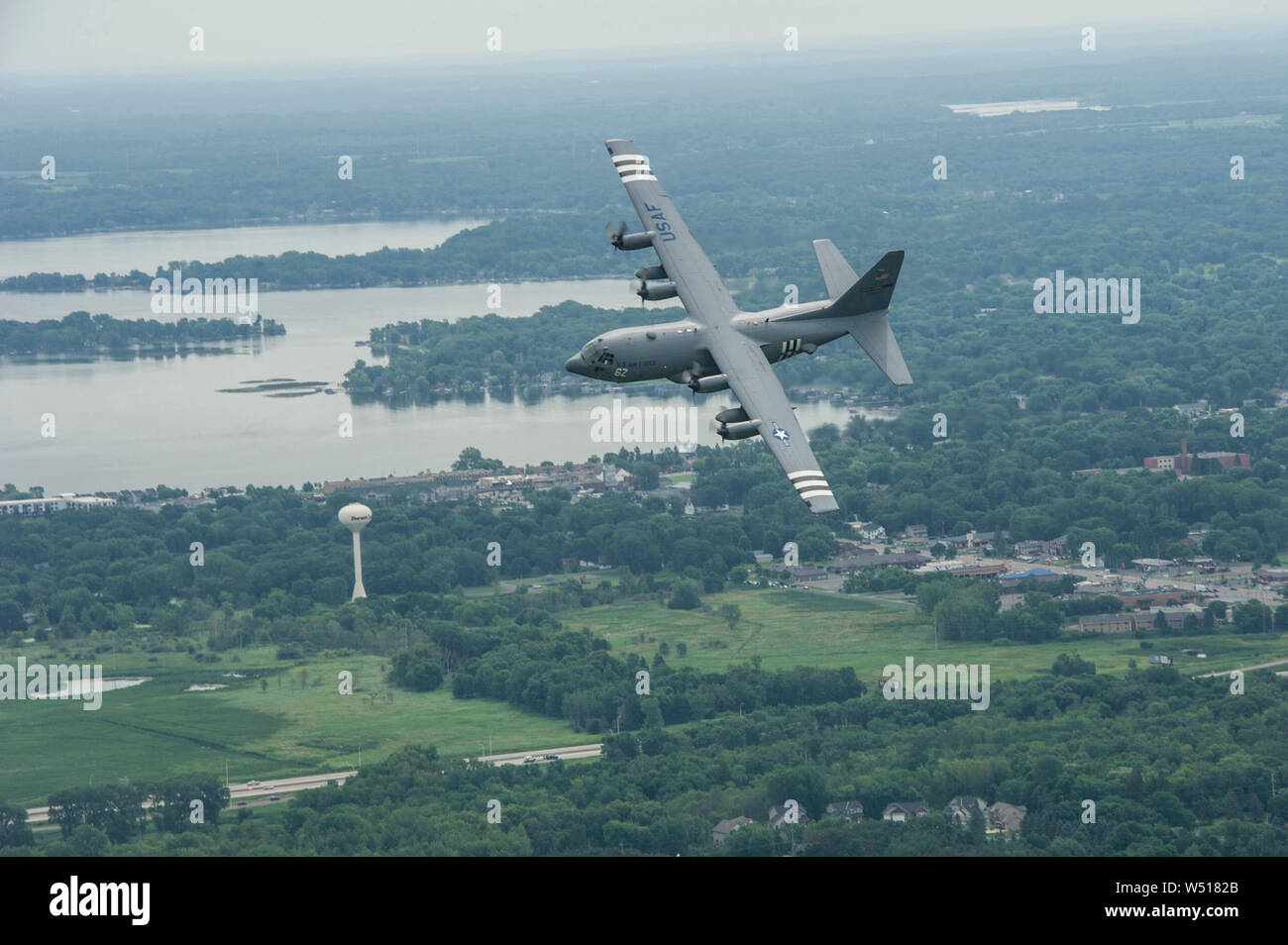 A U.S. Air Force C-130H Hercules aircraft from the 96th Airlift Squadron, Minneapolis-St. Paul Air Reserve Station, Minn., flies over Minnesota, July 16, 2019. Aircraft number 23284 was painted with WWII invasion stripes in honor of the 75th anniversary of D-Day. Originally activated as the 96th Troop Carrier Squadron, the 96th, dropped paratroops of the 101st Airborne Division in Normandy during the D-Day invasion and flew numerous missions to bring in reinforcements and needed supplies during the war. (U.S. Air Force Photo by Tech. Sgt. Amber E. N. Kurka) Stock Photo