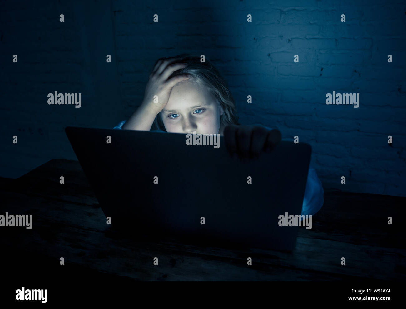 Scared sad girl bullied on line with laptop suffering cyber bullying harassment feeling desperate and intimidated. Child victim of bullying stalker so Stock Photo