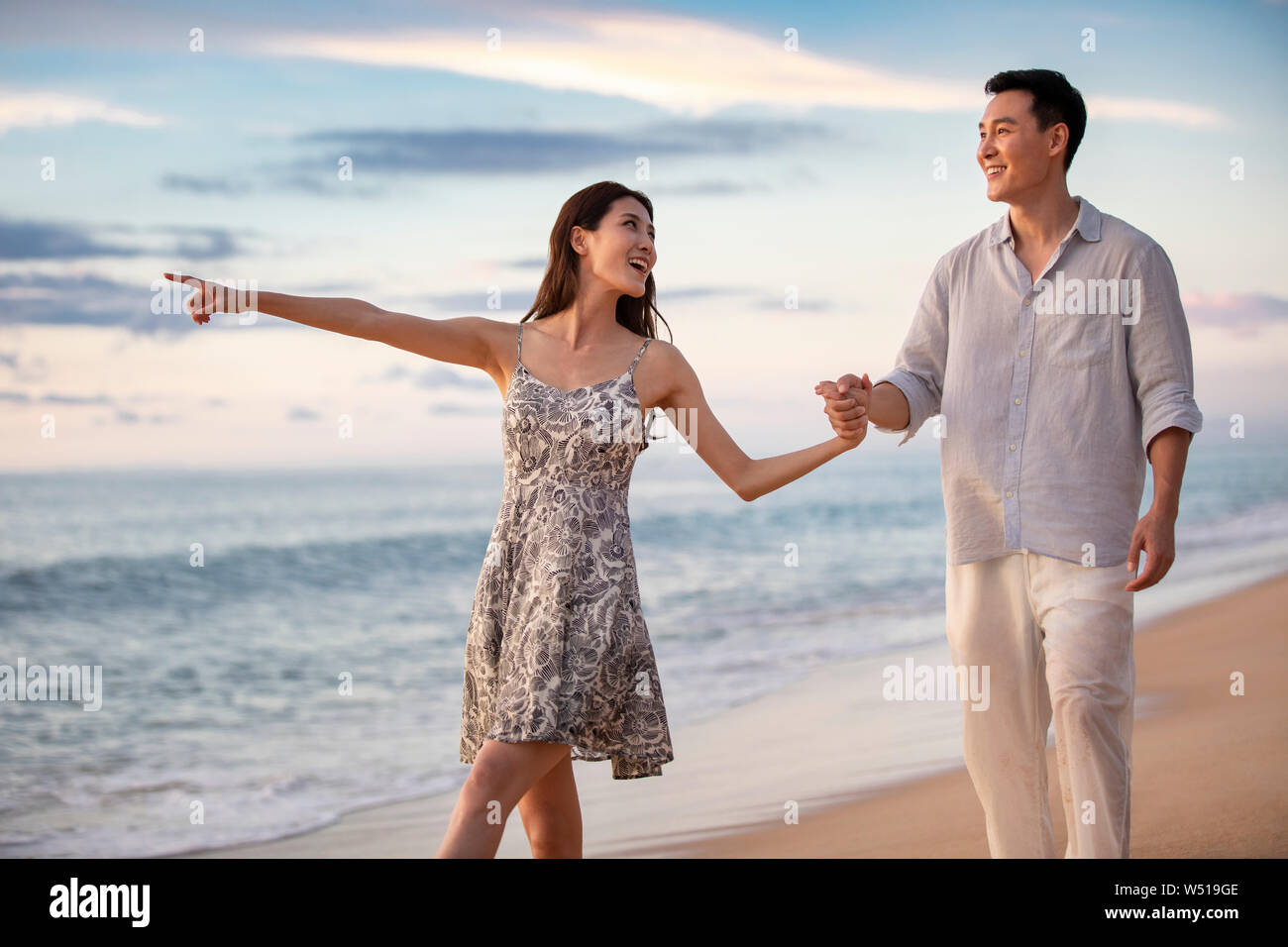 Happy young couple walking on beach Stock Photo - Alamy