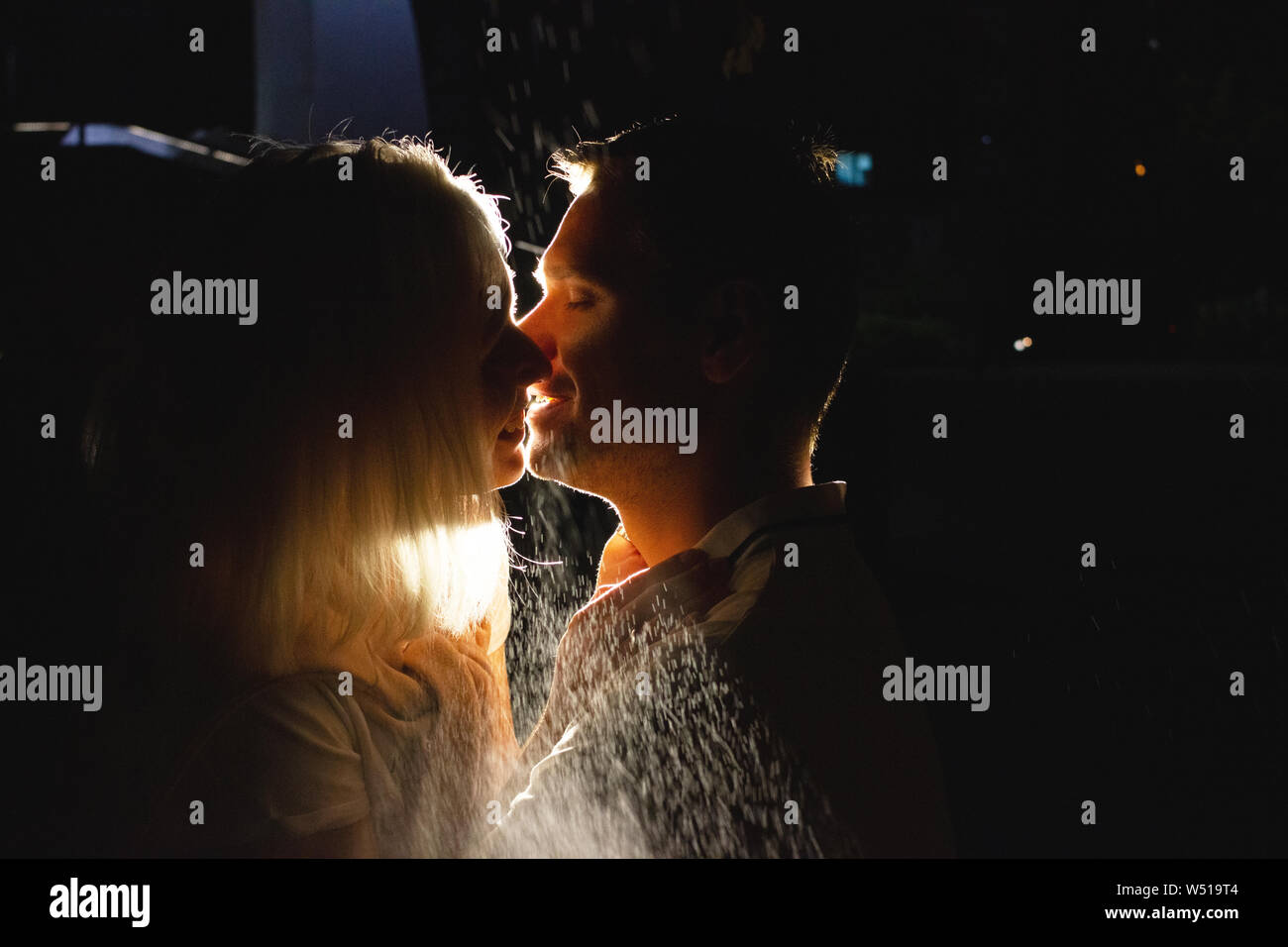 Young happy couple in love kissing in the night under rain. Photo with ...