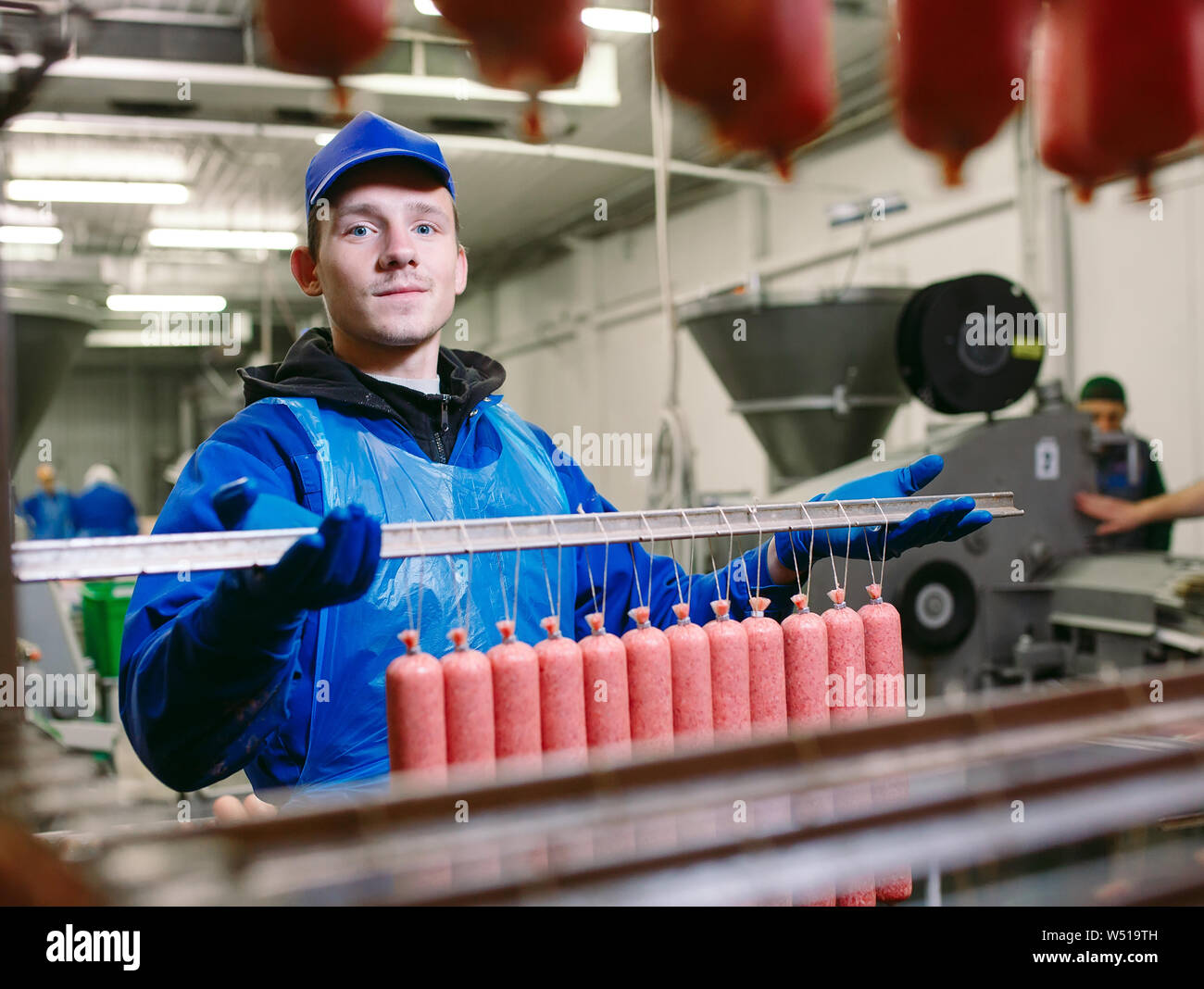 Portrait of butchers processing sausages at meat factory Stock Photo ...