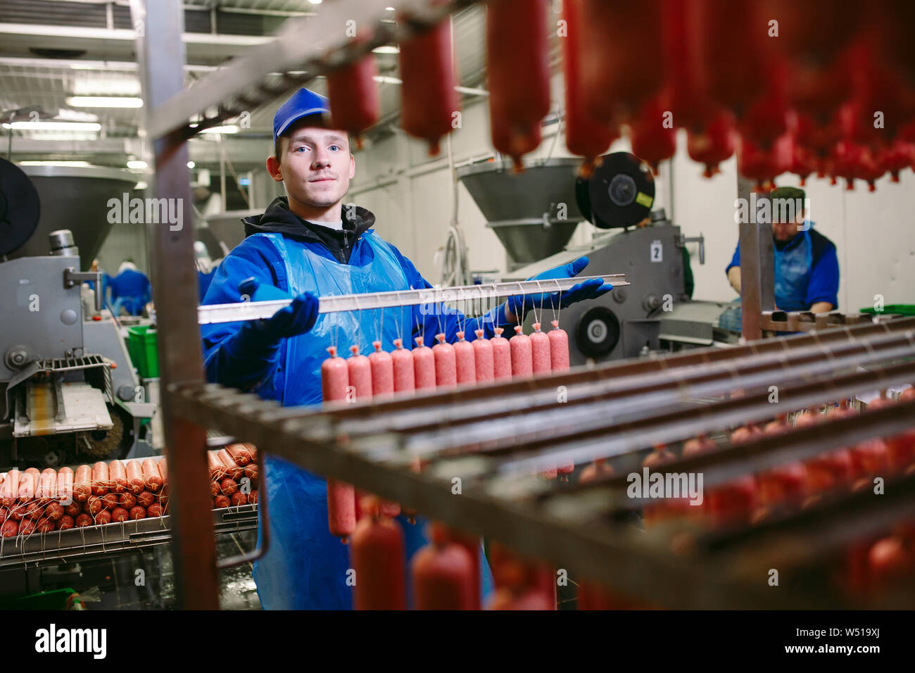 Portrait of butchers processing sausages at meat factory Stock Photo ...