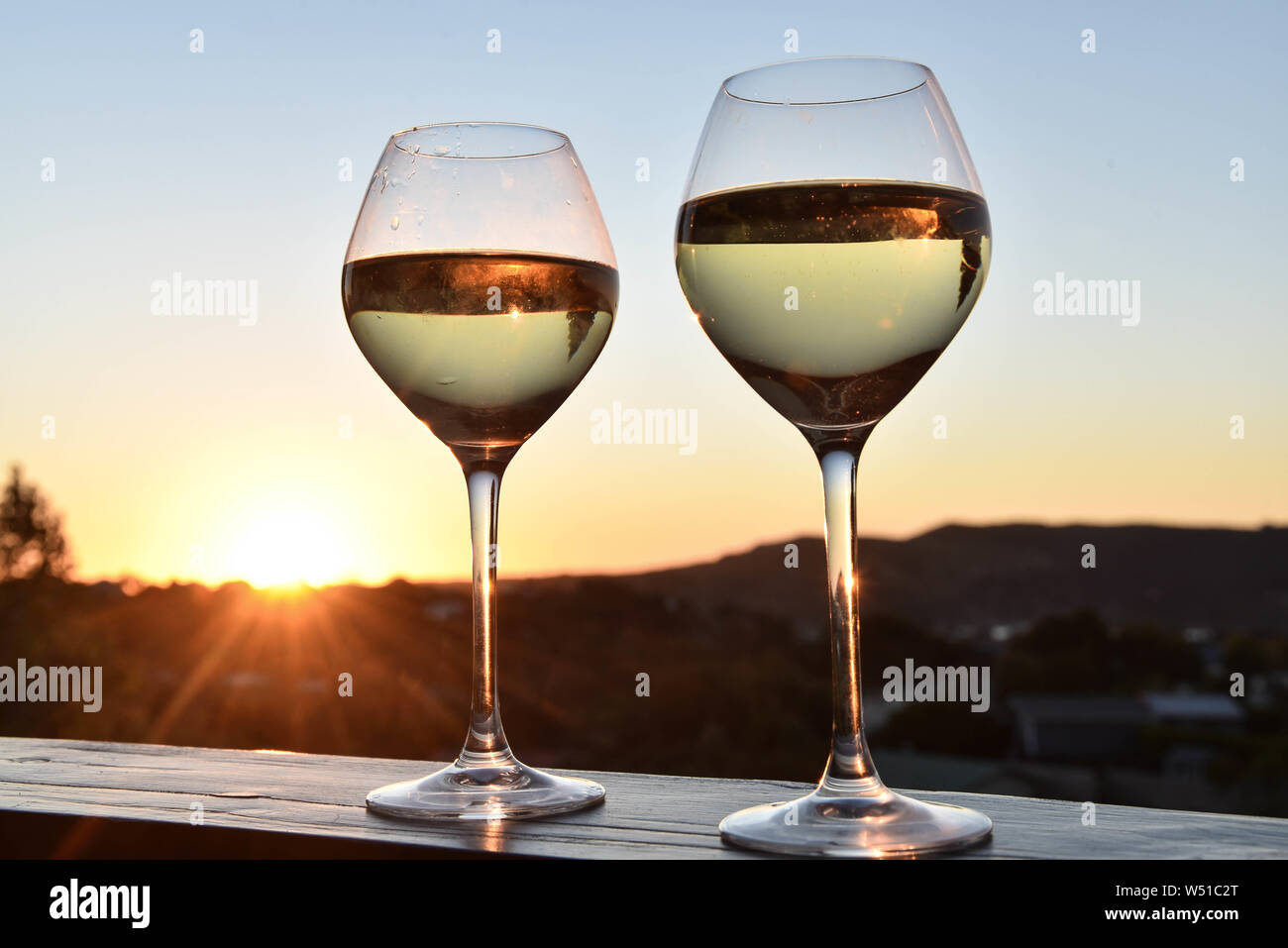 two wine glasses on a wall at sunset Stock Photo