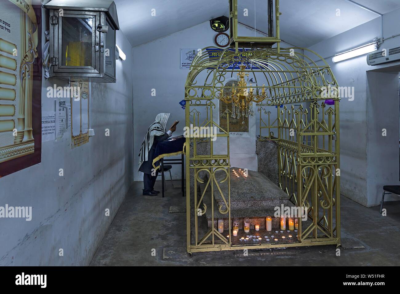Grave of Hasidic Rabbi Elimelech in a gold-plated lattice at the Jewish cemetery of Lezajsk, behind a praying Orthodox Jew, Lezajsk, Poland Stock Photo