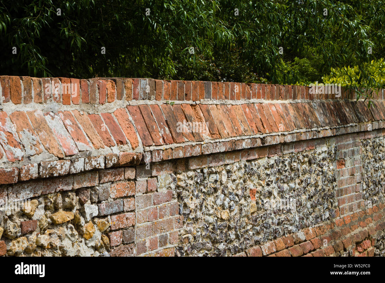 A traditional brick and flint wall with decorative copings in the