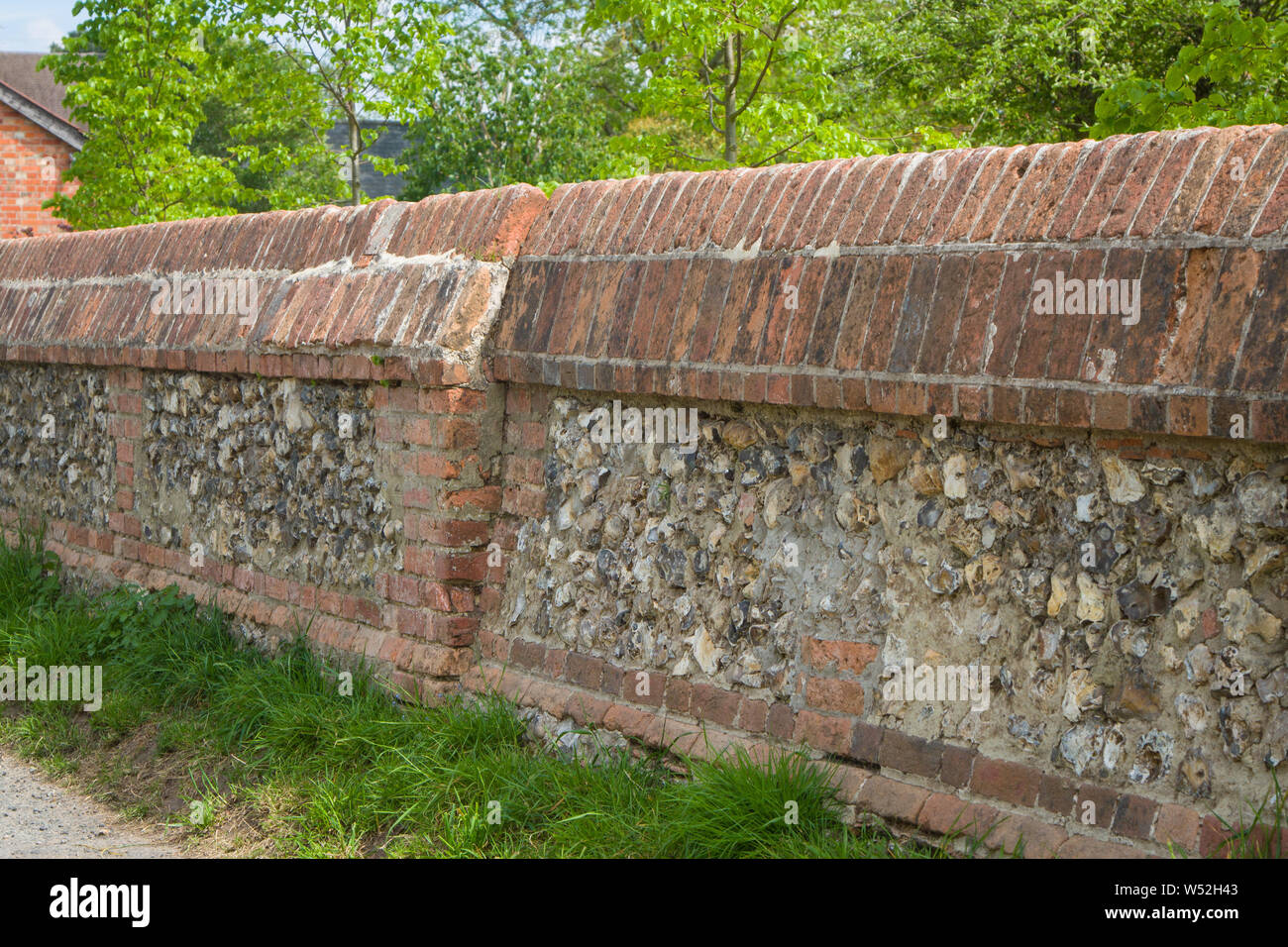 A traditional brick and flint wall with decorative copings in the