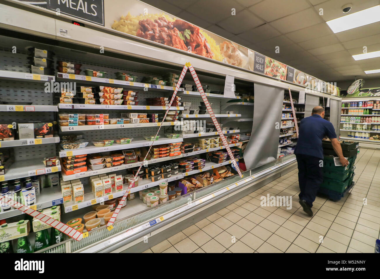London UK. 26th  July 2019.**Permission Granted**. Refrigerated shelves at a local Tesco supermarket in Wimbledon are covered by screens as the refrigeration broke down due to extreme heat which is likely to affect produce and dairy and meat products .A study has found Supermarket giant Tesco consumed more than 6 million mega-watt hours of non-renewable energy in 2018/19 – an amount equivalent to powering eight cities Credit: amer ghazzal/Alamy Live News Stock Photo