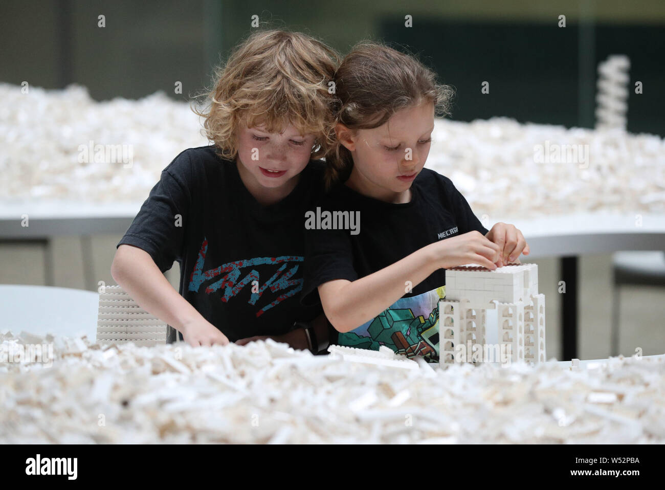 Hunter Tagholm (left) and Finn Beale (right), both aged 8, begin putting together some of the tonne of Lego bricks for Olafur Eliasson's cubic structural evolution project 2004 artwork in the Tate Modern's Turbine Hall, London. Stock Photo
