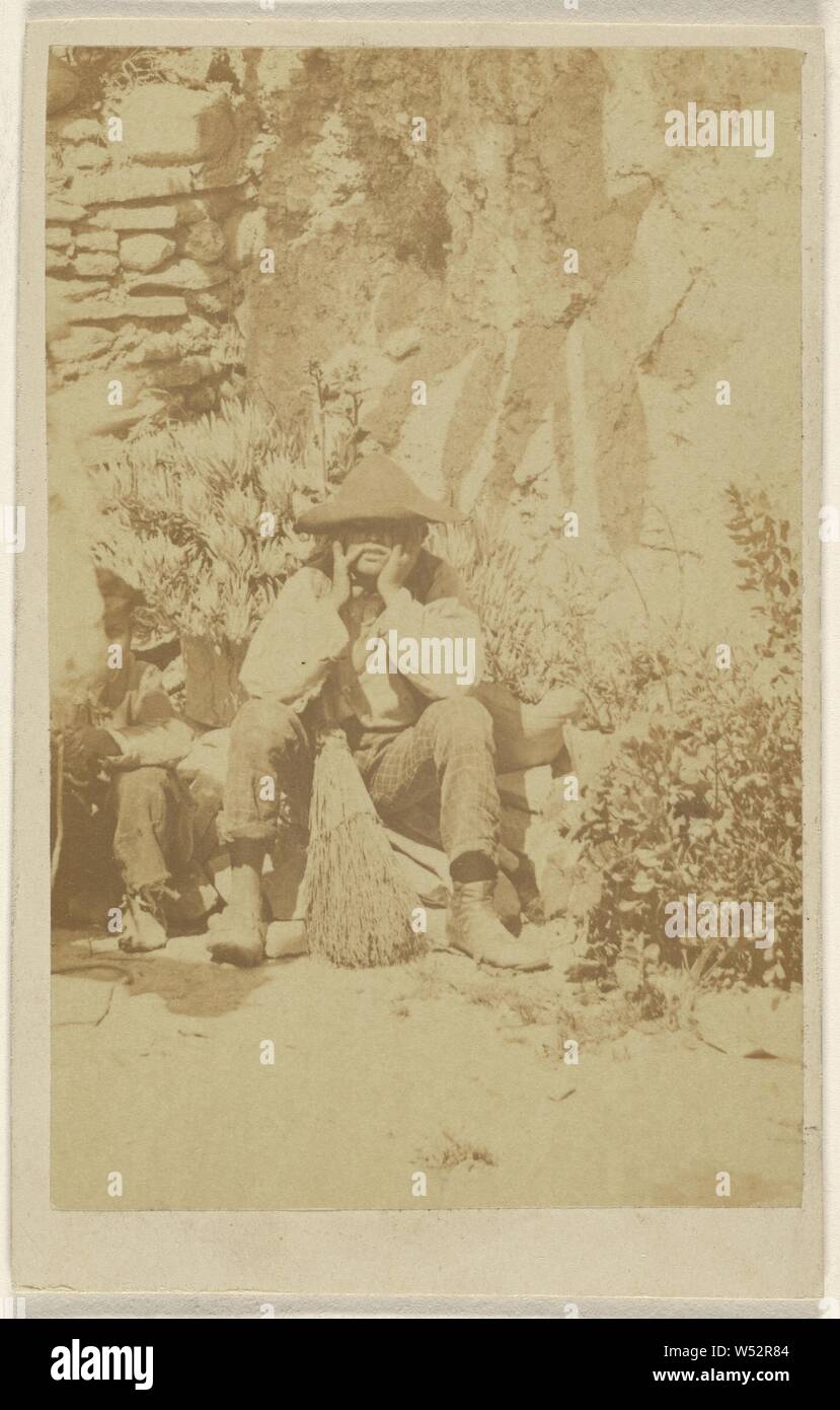 Unidentified man wearing a tricorn, seated, hands to face, a broom between his legs, Unknown, 1870–1875, Albumen silver print Stock Photo