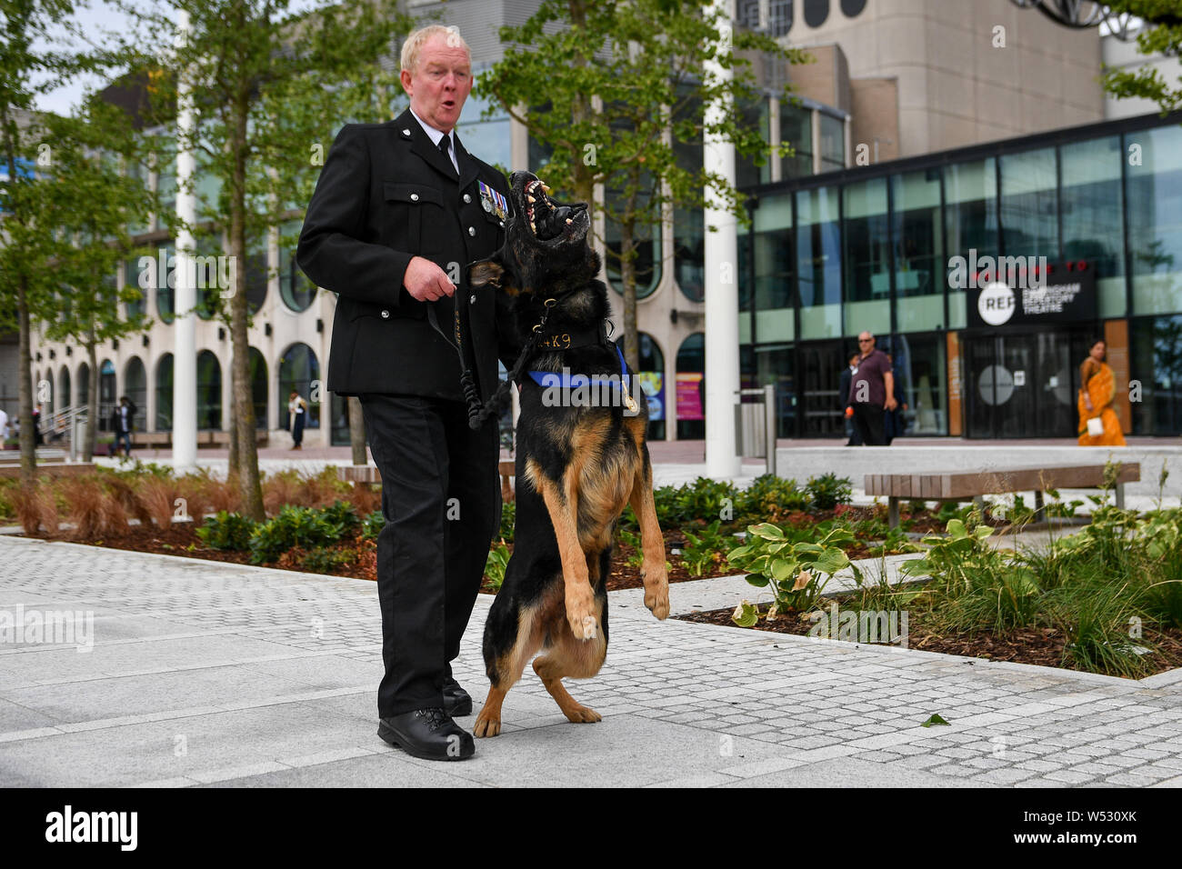 Retired West Mercia Police dog handler PC Mike Davey and retired police dog Bacca, who was brutally stabbed protecting his handler and the public while serving with West Mercia Police, after receiving the PDSA's Gold Medal &ETH; which the charity regards as the animal equivalent of the George Cross &ETH; following a ceremony at Birmingham Repertory Theatre on Friday. Stock Photo
