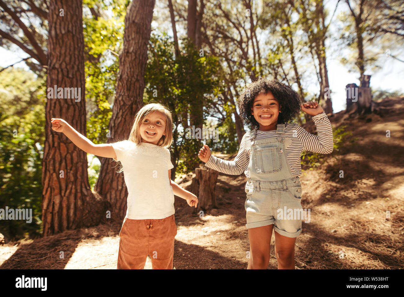 Cute girls having fun together in forest. Kids dancing in park. Stock Photo